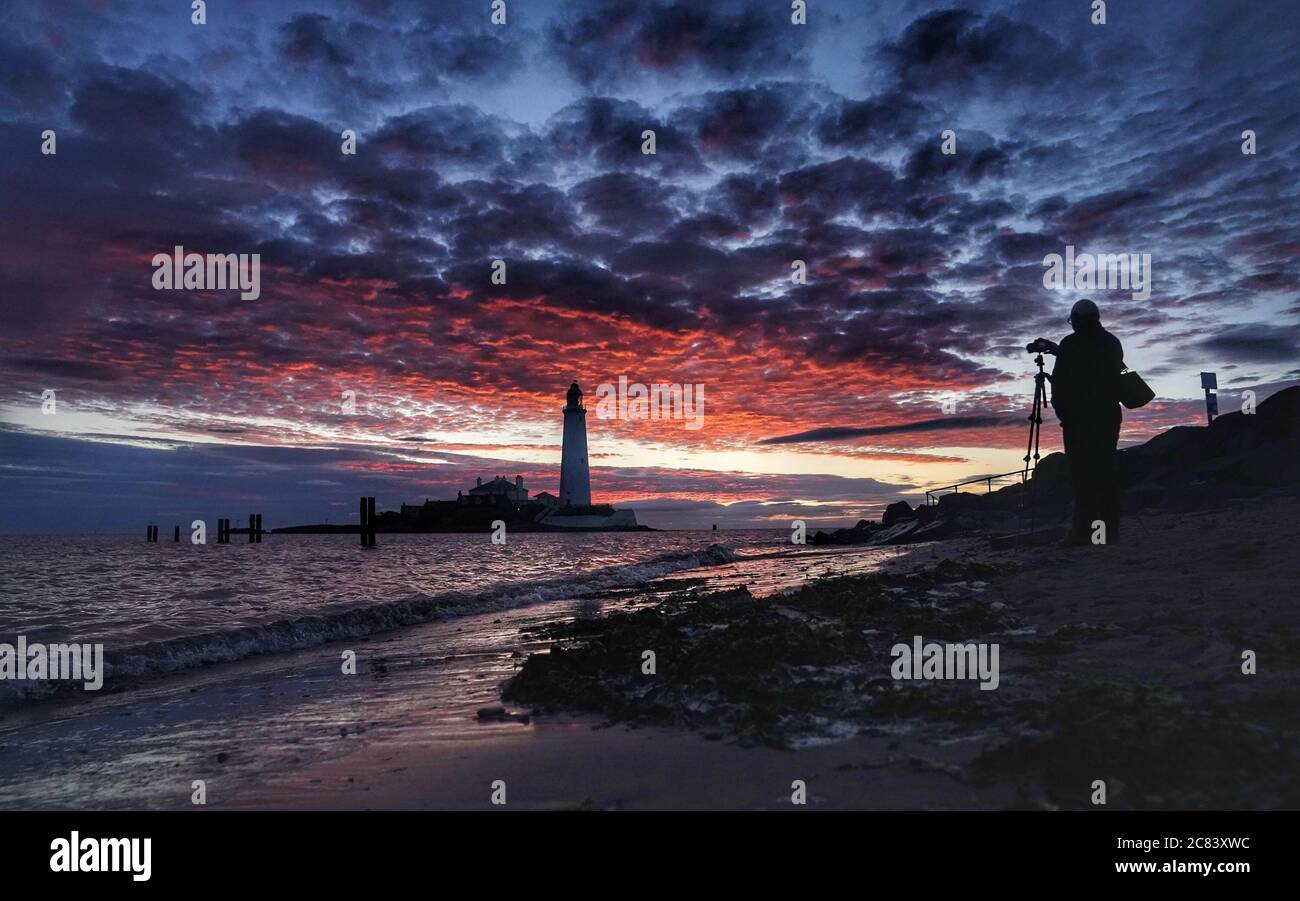 A photographer lines up his shot at sunrise at St Mary's Lighthouse in Whitley Bay in the early hours of Tuesday morning. Picture date: Tuesday July 21, 2020. Photo credit should read: Owen Humphreys/PA Wire Stock Photo