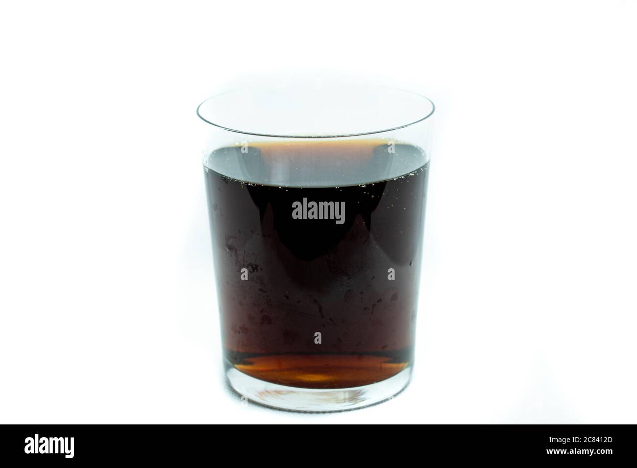 Glass filled with a brown liquid isolated on a white background Stock Photo