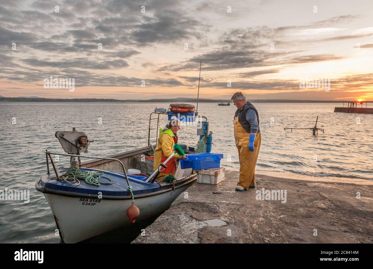 Knockadoon, Cork, Ireland. 21st July, 2020. Father and son Vincent and Barney O'Brien load bait on to their boat at sunrise prior to headng out for a days fishing in Knockadoon, Co. Cork, Ireland. - Credit; David Creedon / Alamy Live News Stock Photo