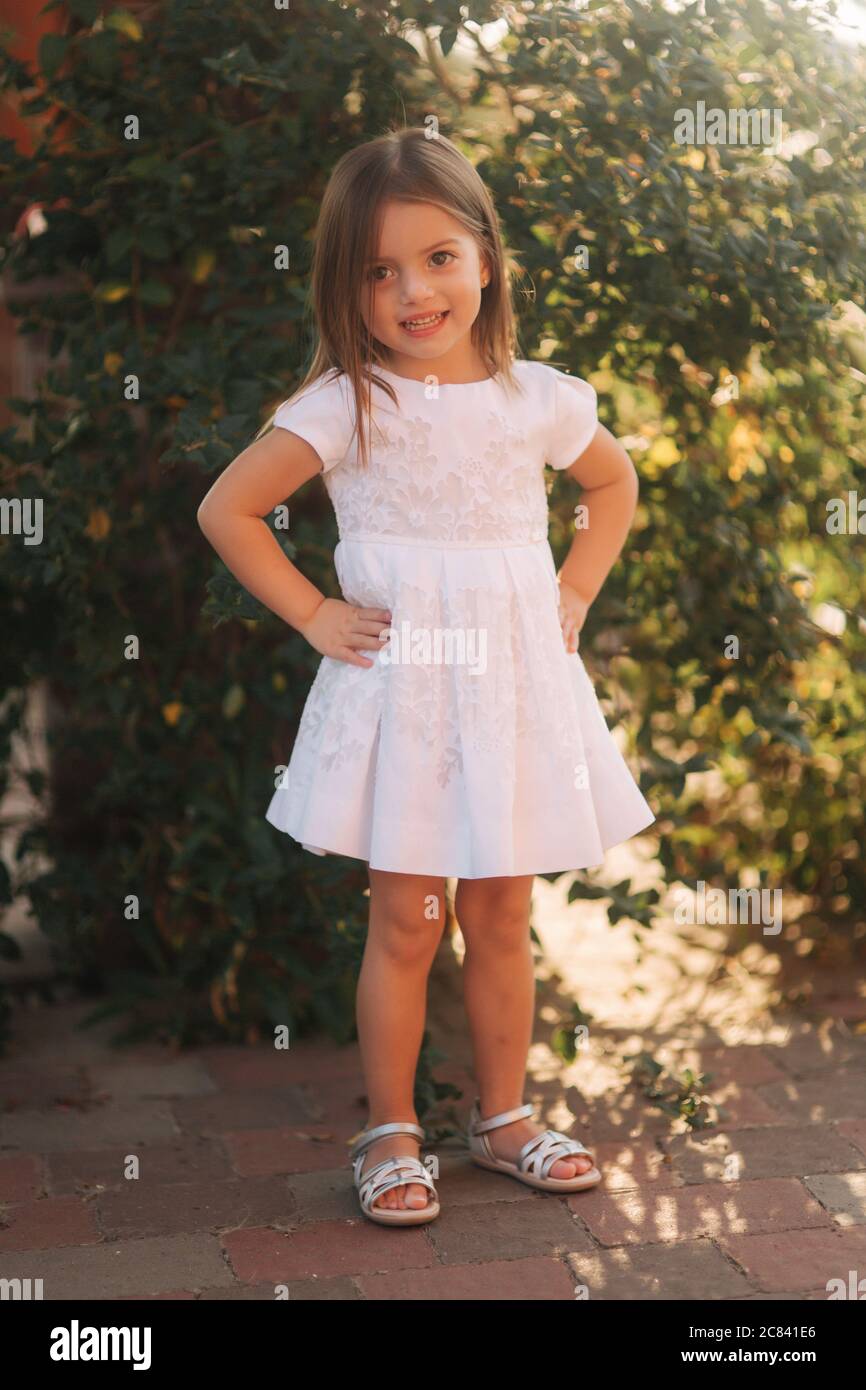 Beautiful little girl in white dress walking outdoors on back yaer of ...