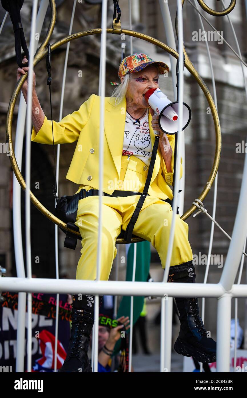 London, UK.  21 July 2020.  Dame Vivienne Westwood re-enters public life, after being in shielding during the COVID-19 lockdown, by being harnessed into a giant birdcage and suspended 10 feet in the air in front of The Old Bailey Criminal Court in protest about the U.S. extradition trial of Julian Assange, which is to recommence at the Old Bailey on 7 September.  She is dressed in a yellow trouser suit, enacting the metaphor of ‘The Canary In Coal Mine’, which is indicative of 'Assange being sacrificed for identifying ‘poison’ in the system'.   Credit: Stephen Chung / Alamy Live News Stock Photo