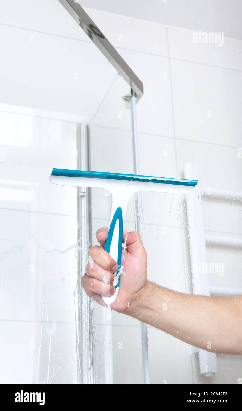 hand with glass scraper cleans glass in shower Stock Photo Alamy