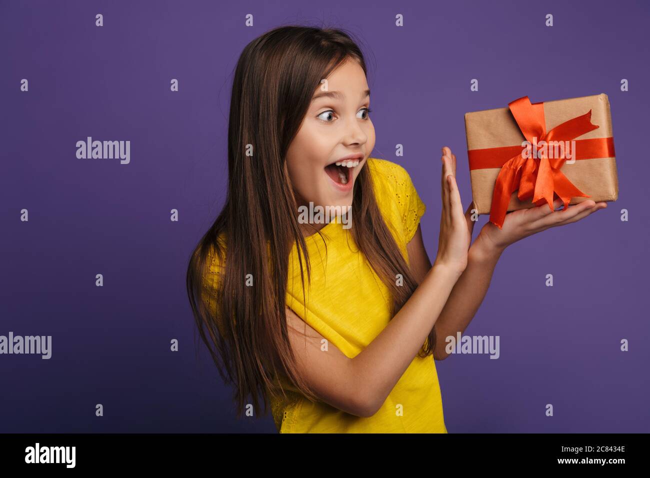 Photo of excited beautiful girl holding gift box and expressing ...