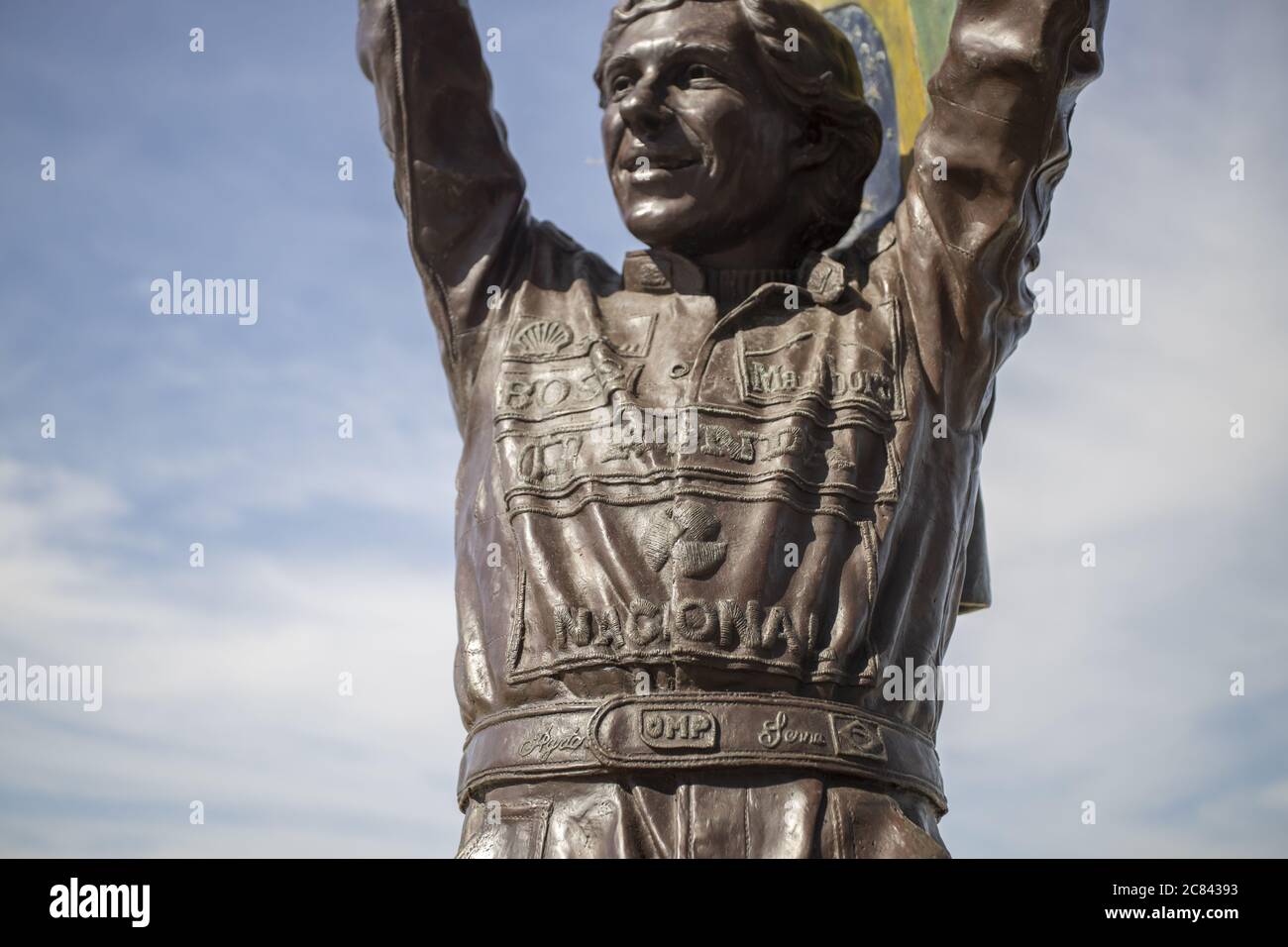 RIO DE JANEIRO, BRAZIL - Jul 12, 2020: Closeup of bronze statue of Ayrton Senna holding a Brazilian flag up high with his racing suite full of company Stock Photo
