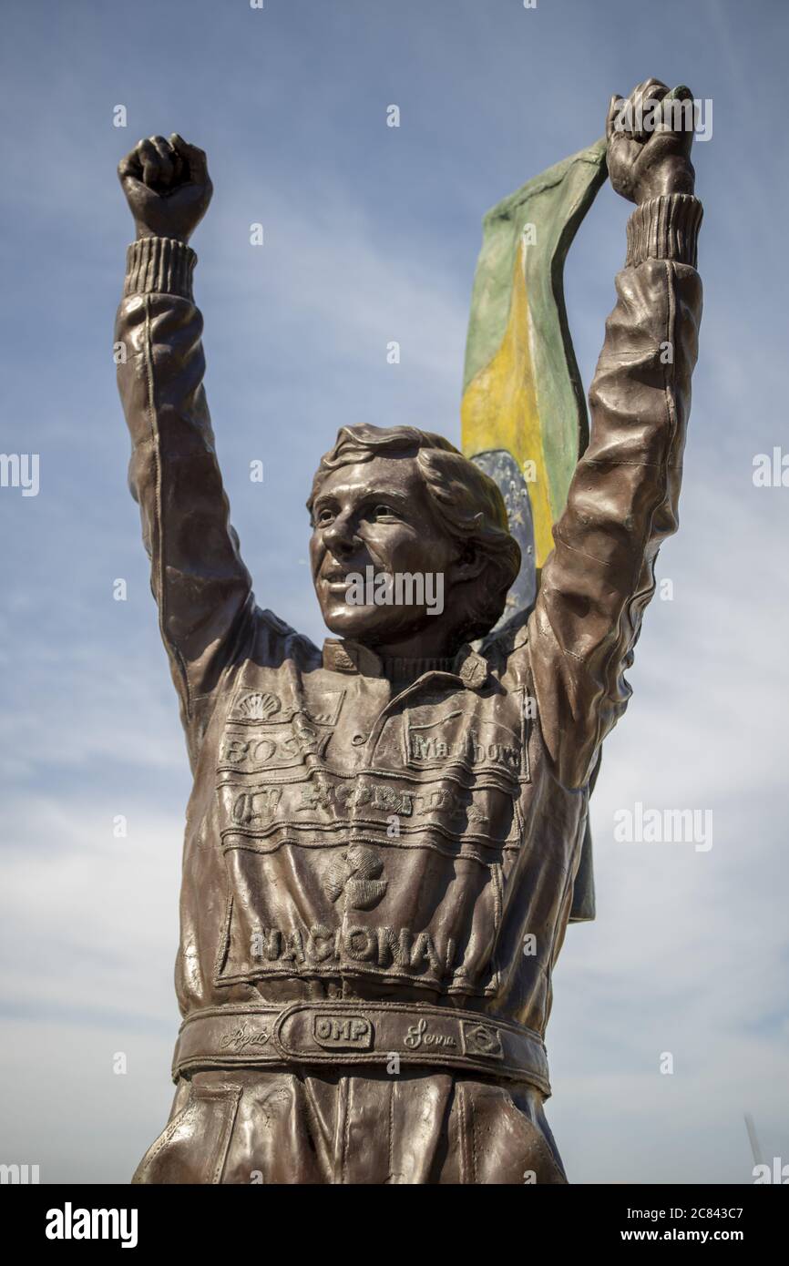 RIO DE JANEIRO, BRAZIL - Jul 12, 2020: Bronze statue of Ayrton Senna holding a Brazilian flag up high with his racing suite full of company sponsor lo Stock Photo