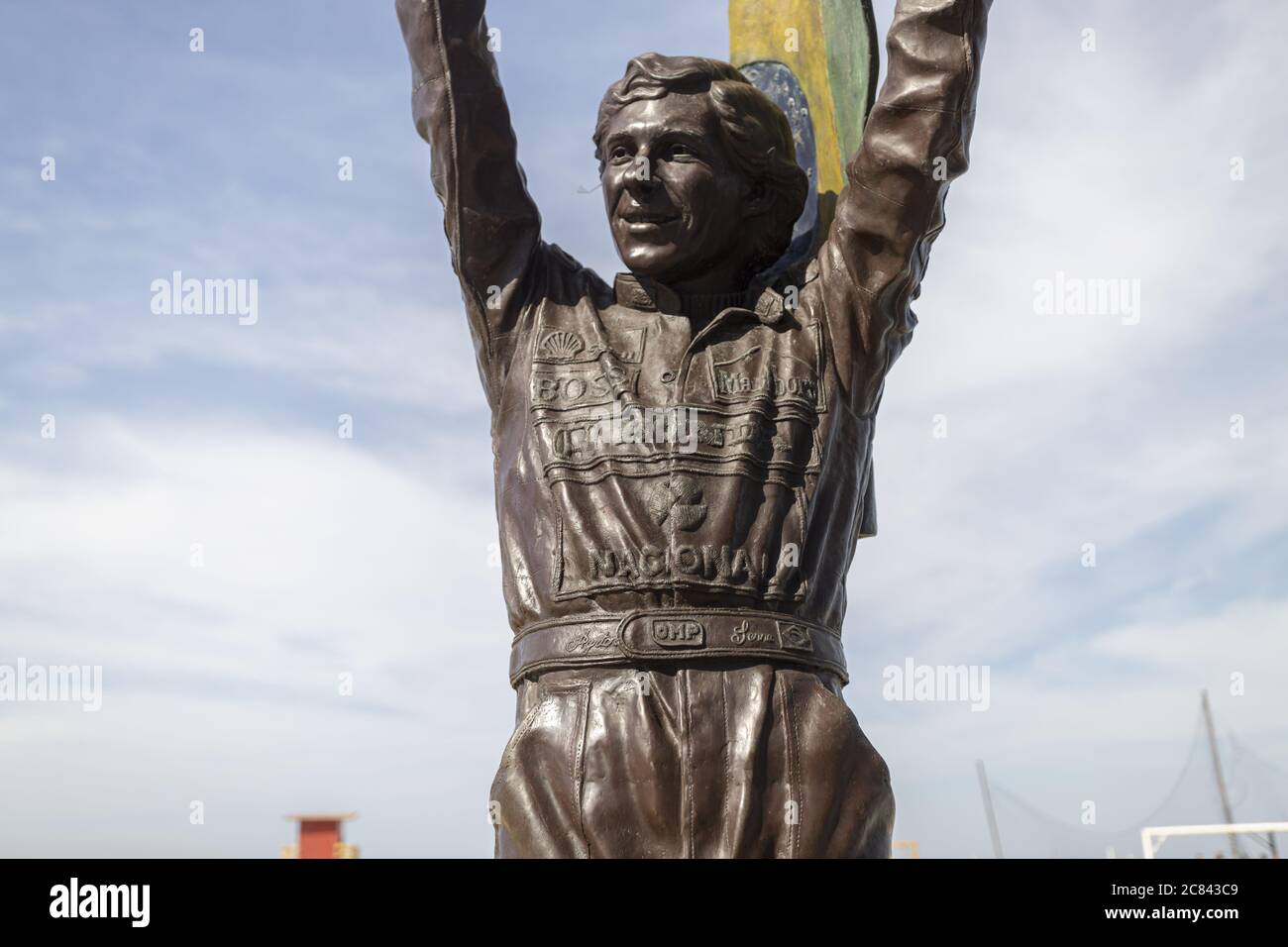RIO DE JANEIRO, BRAZIL - Jul 12, 2020: Bronze statue of Ayrton Senna holding a Brazilian flag up high with his racing suite full of company sponsor lo Stock Photo