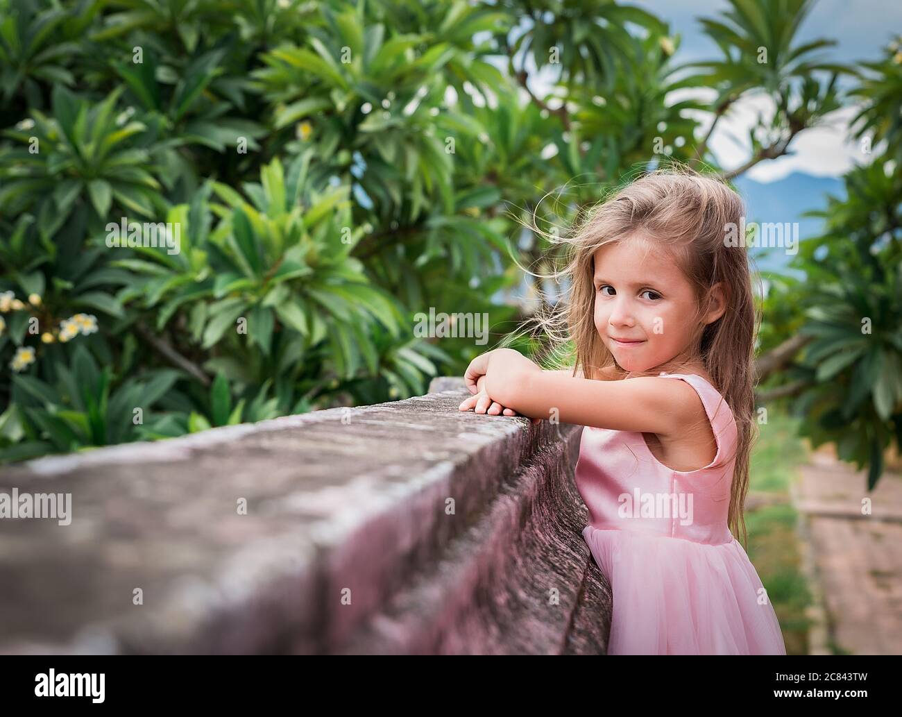 portrait of a happy little girl in pink dress outdoor, near wall Stock ...