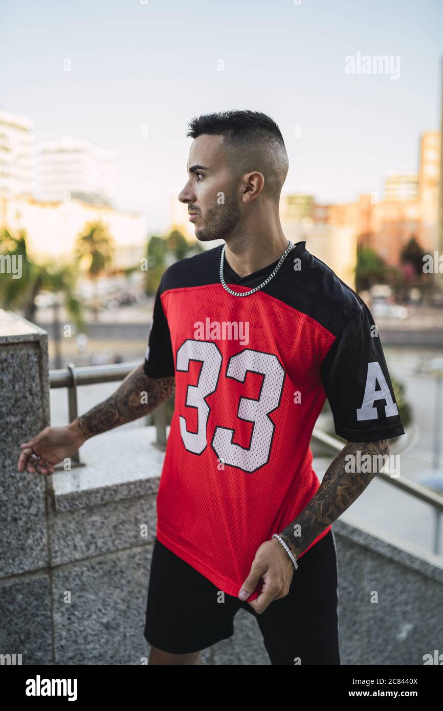 European hip male in a sporty outfit with red and black shorts and