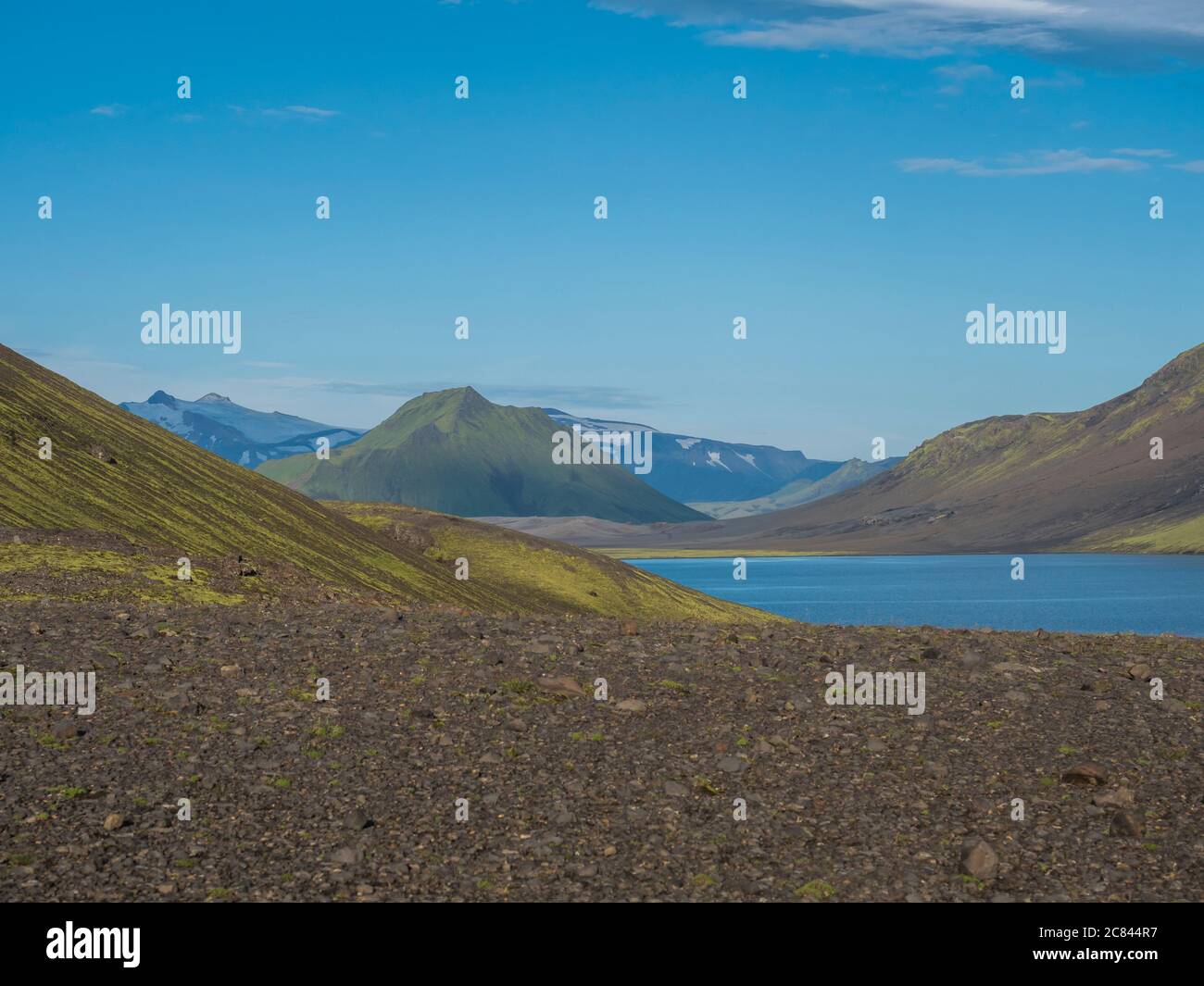 Beautiful landscape of blue Alftavatn lake with snow covered mountains and green hills and blue sky background. Summer landscape of the Fjallabak Stock Photo