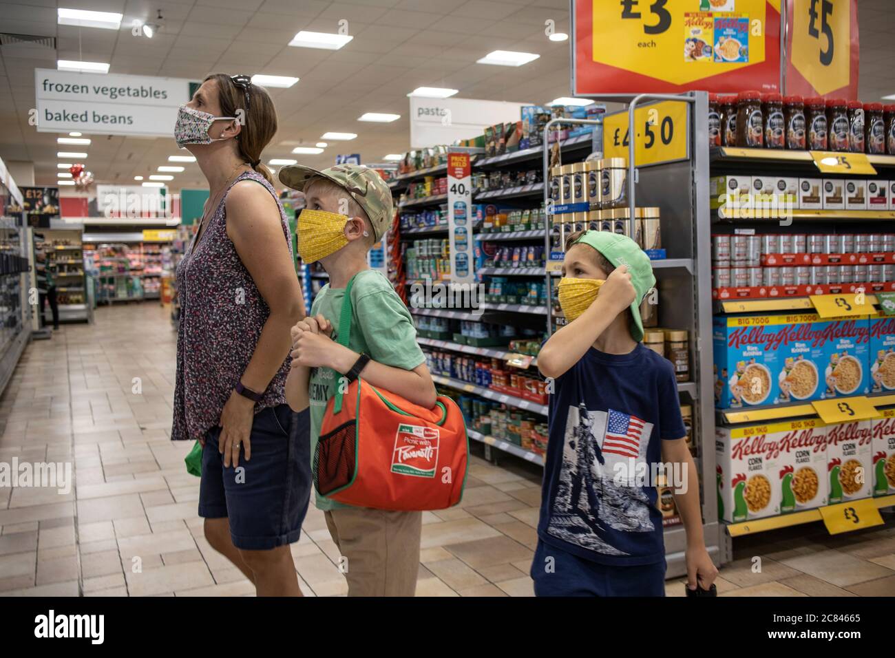 Family shopping in Morrisons UK supermarket wearing protective facemarks to protect against the spread of infection of coronavirus, London, England UK Stock Photo