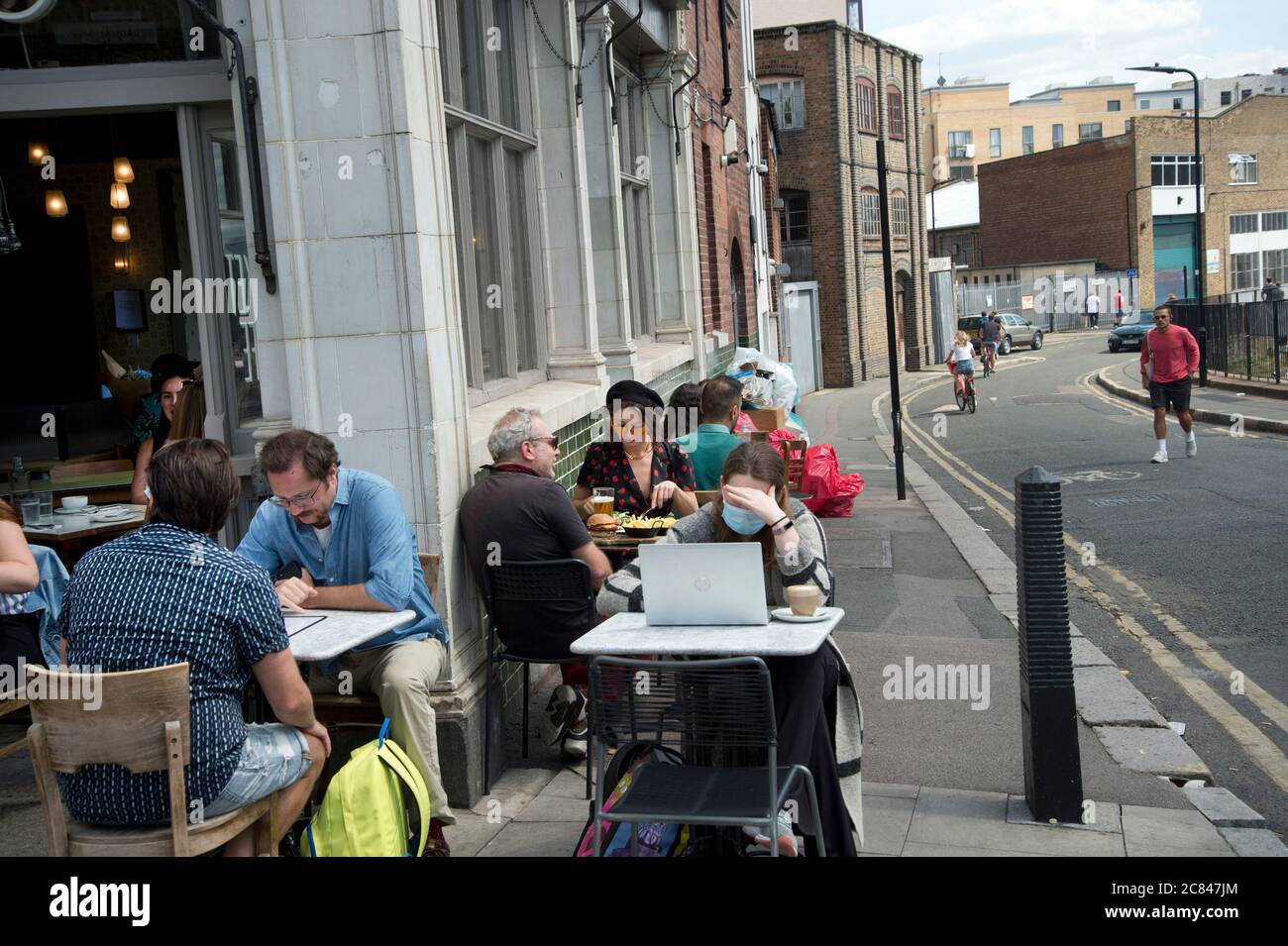 Hackney, London, UK. Broadway market. Reopened cafe with people sitting and working outside. Stock Photo