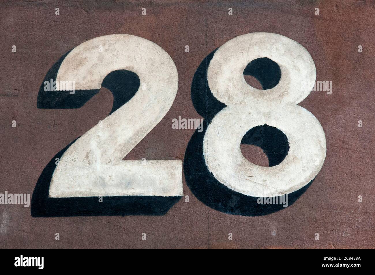 The Door Number 28 Hand Painted In White With A Shadow Effect On A Wall Stock Photo