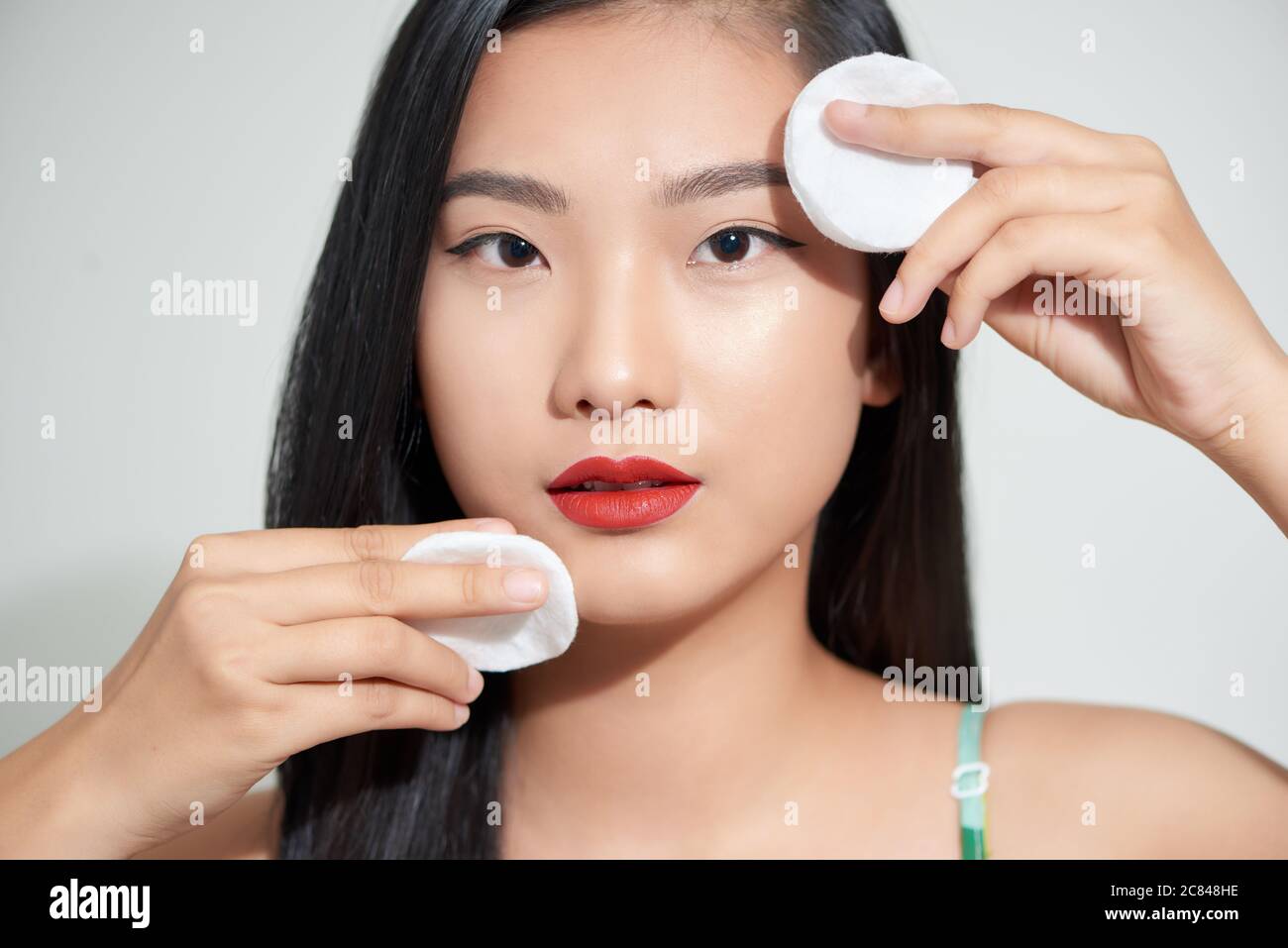 Healthy fresh asian girl removing makeup from her face with cotton pad