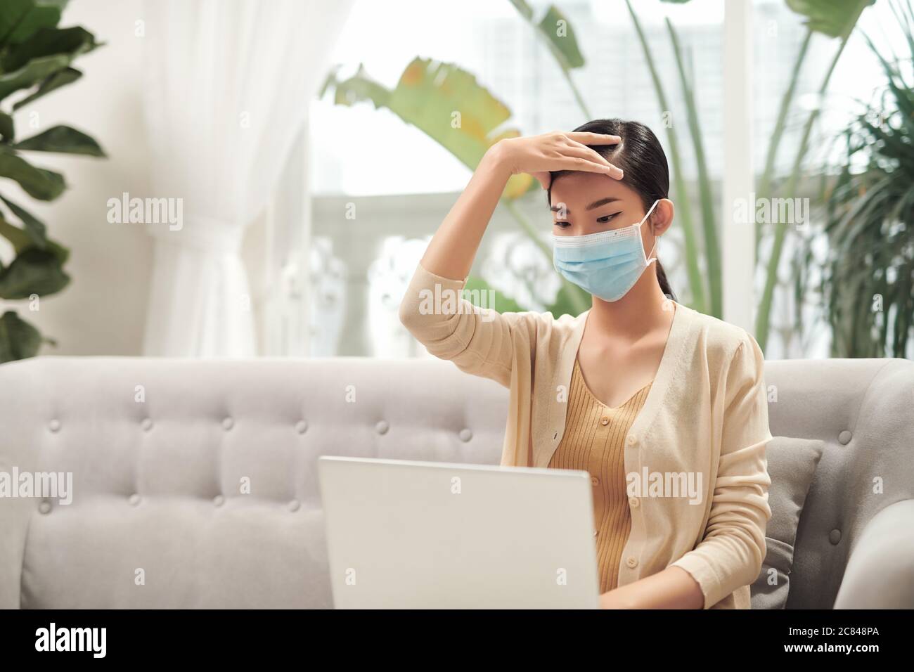 Woman in quarantine for Coronavirus wearing protective mask and smart working Stock Photo
