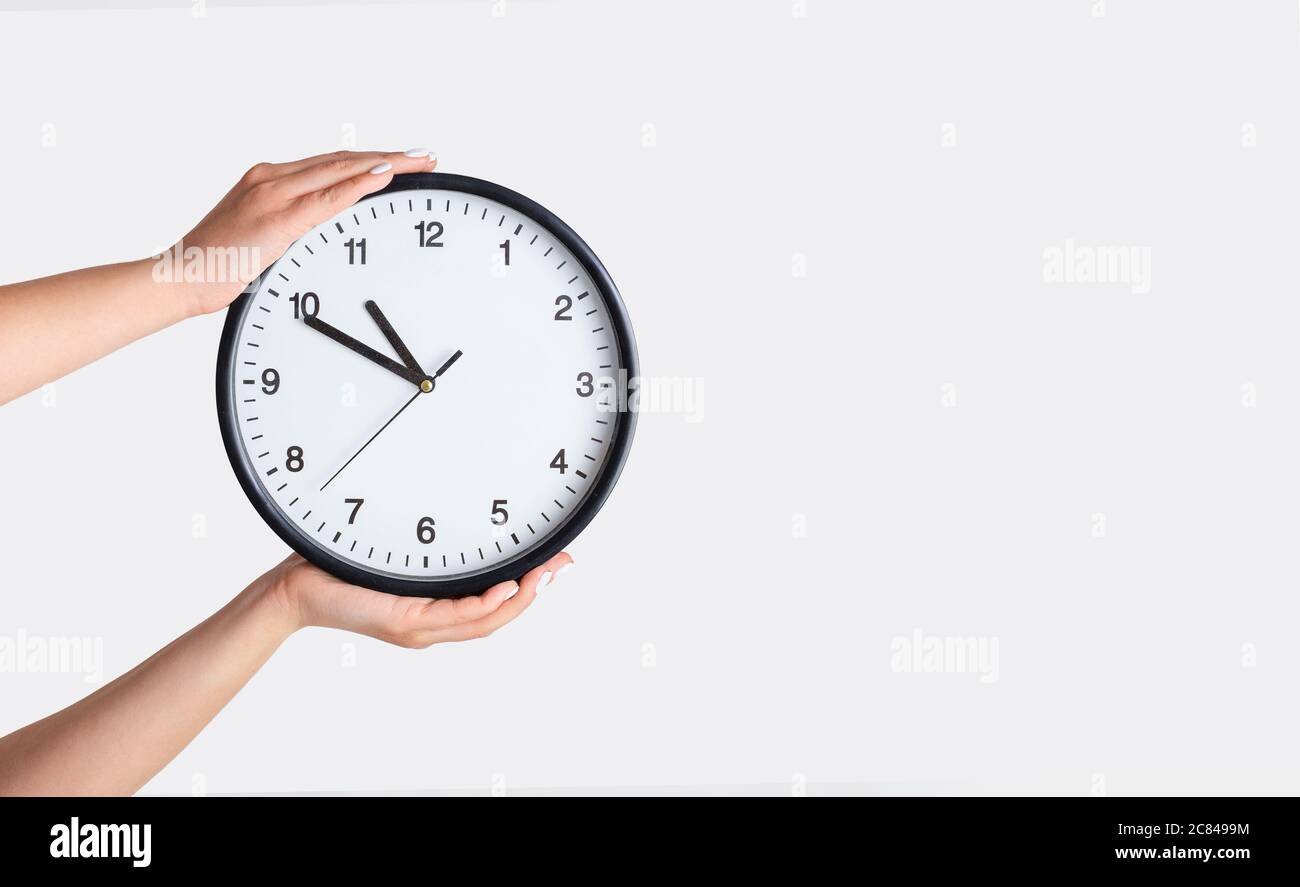 Time management. Female hands holding clock on white background, closeup. Copy space Stock Photo