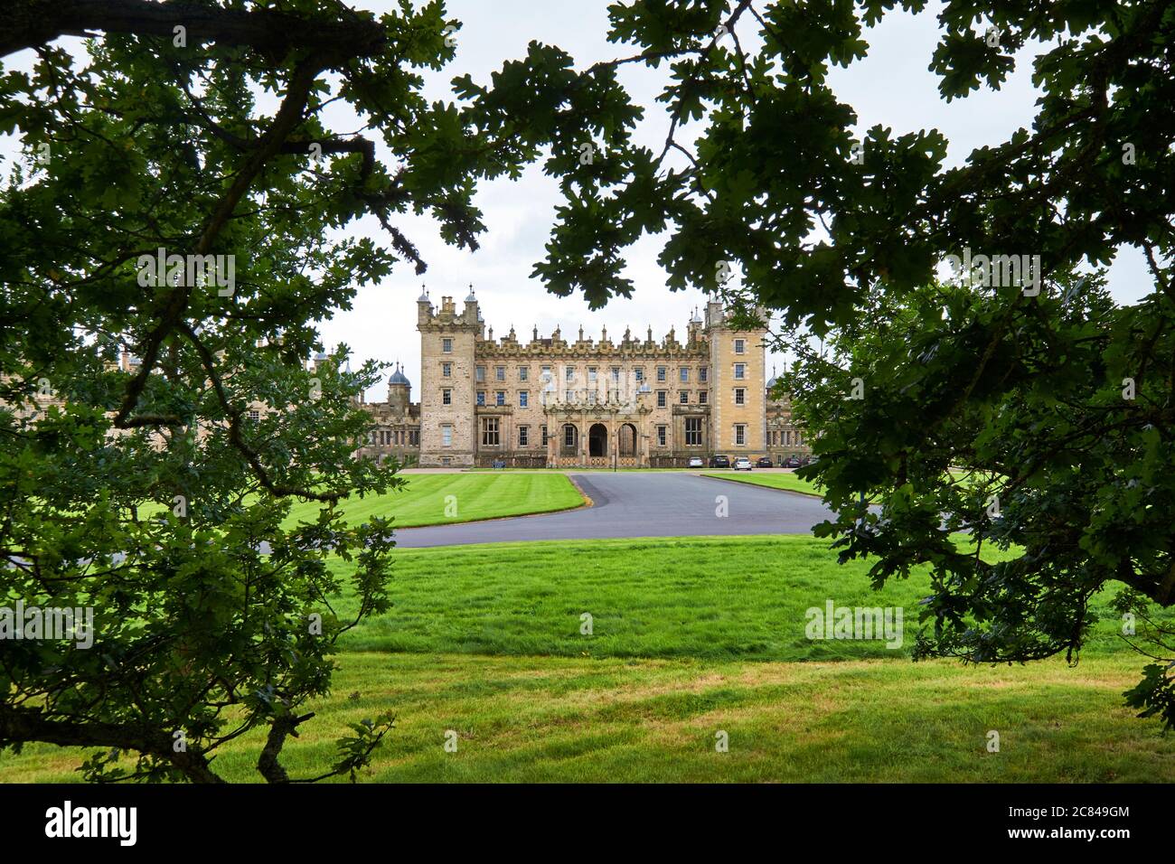 frontal view of Floors Castle and driveway framed by oak tree leaves Stock Photo