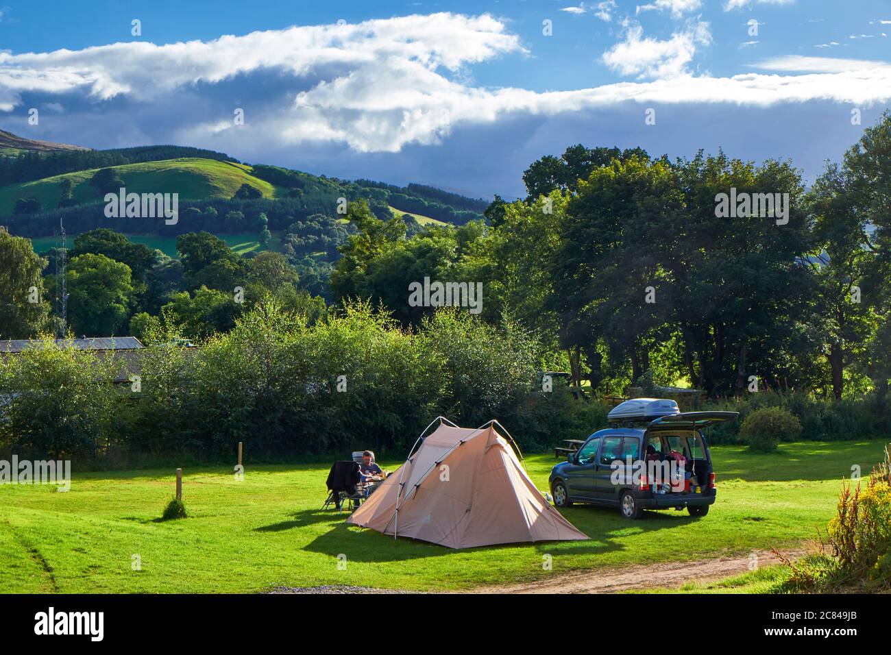 Idyllic scene with tent, tent owner and vehicle on camping plot at Glentrees campsite in the Scottish Borders Stock Photo