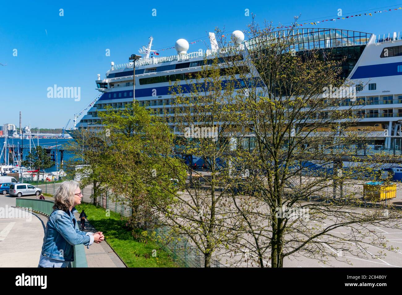 Frau bestaunt ein AIDA Kreuzfahrtschiff am Ostseekai in Kiel Stock Photo
