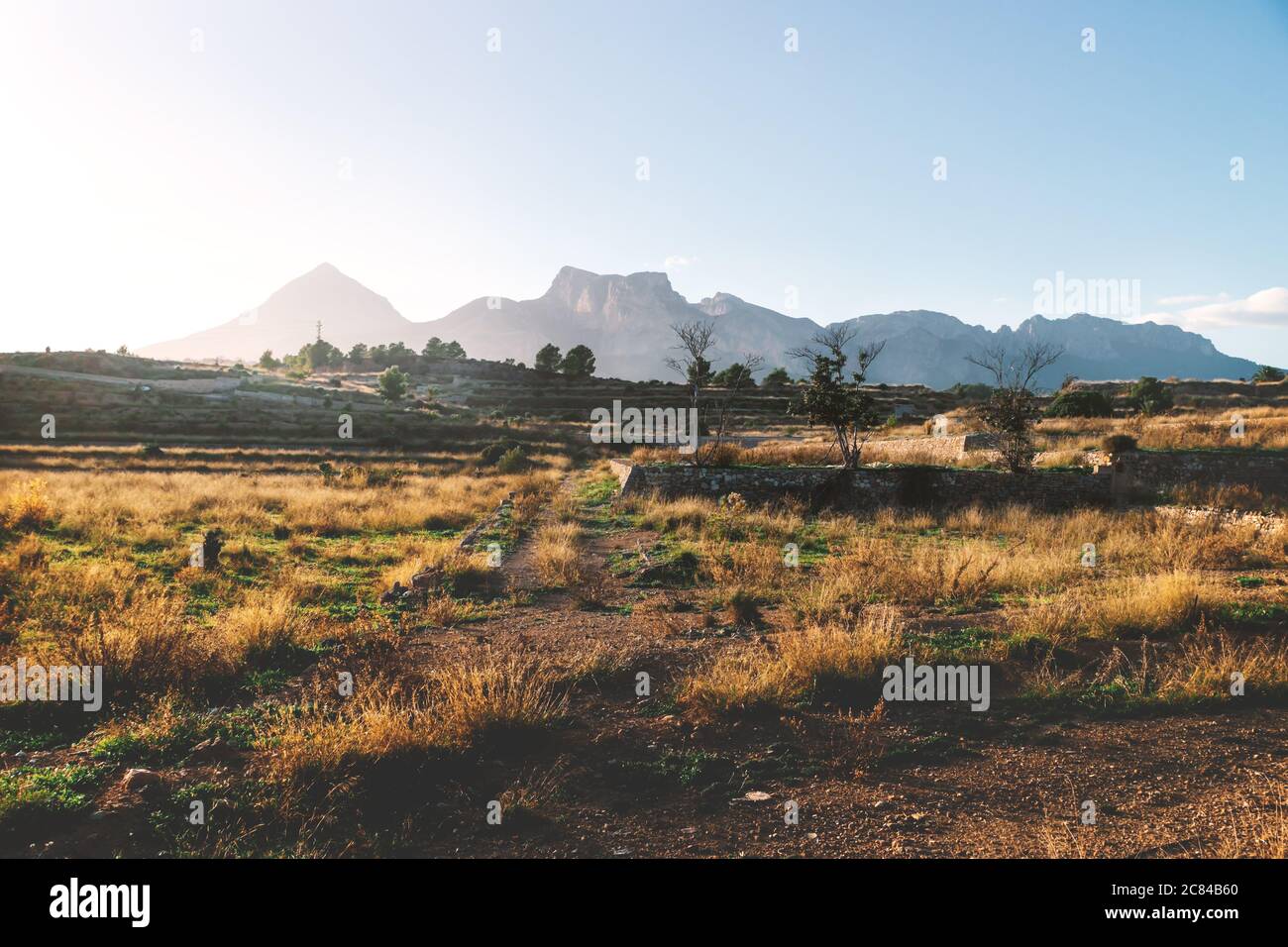 Dry former farmland on the countryside of Costa Blanca during sunset with lit mountains, La Nucia, Spain Stock Photo