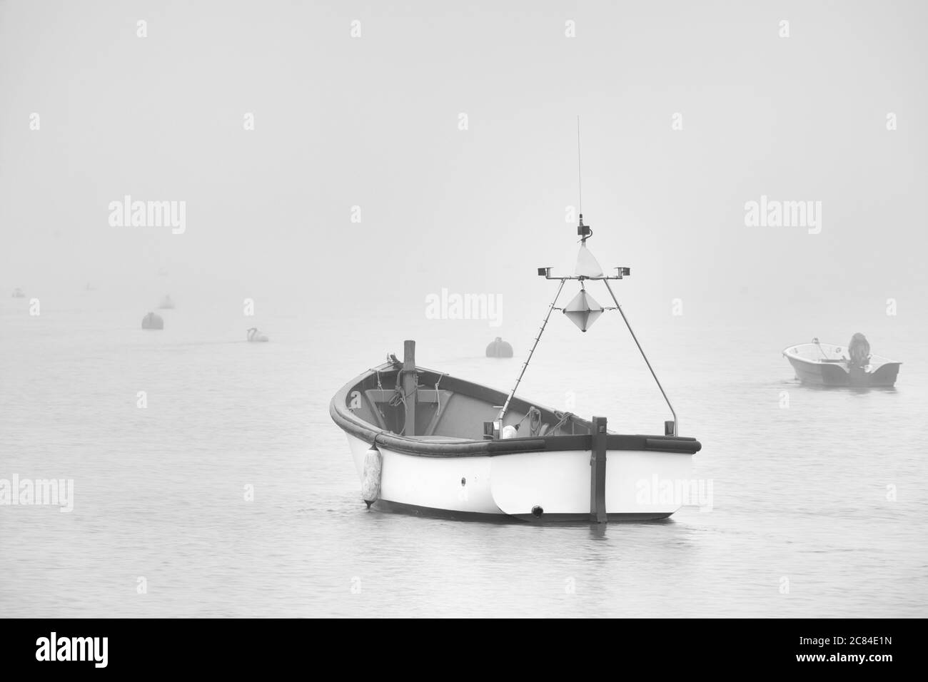 Heavy fog rolling in off of the North Sea, up the River Ore enveloping a small boat in Orford harbour. This photograph was taken from Orford Quay earl Stock Photo