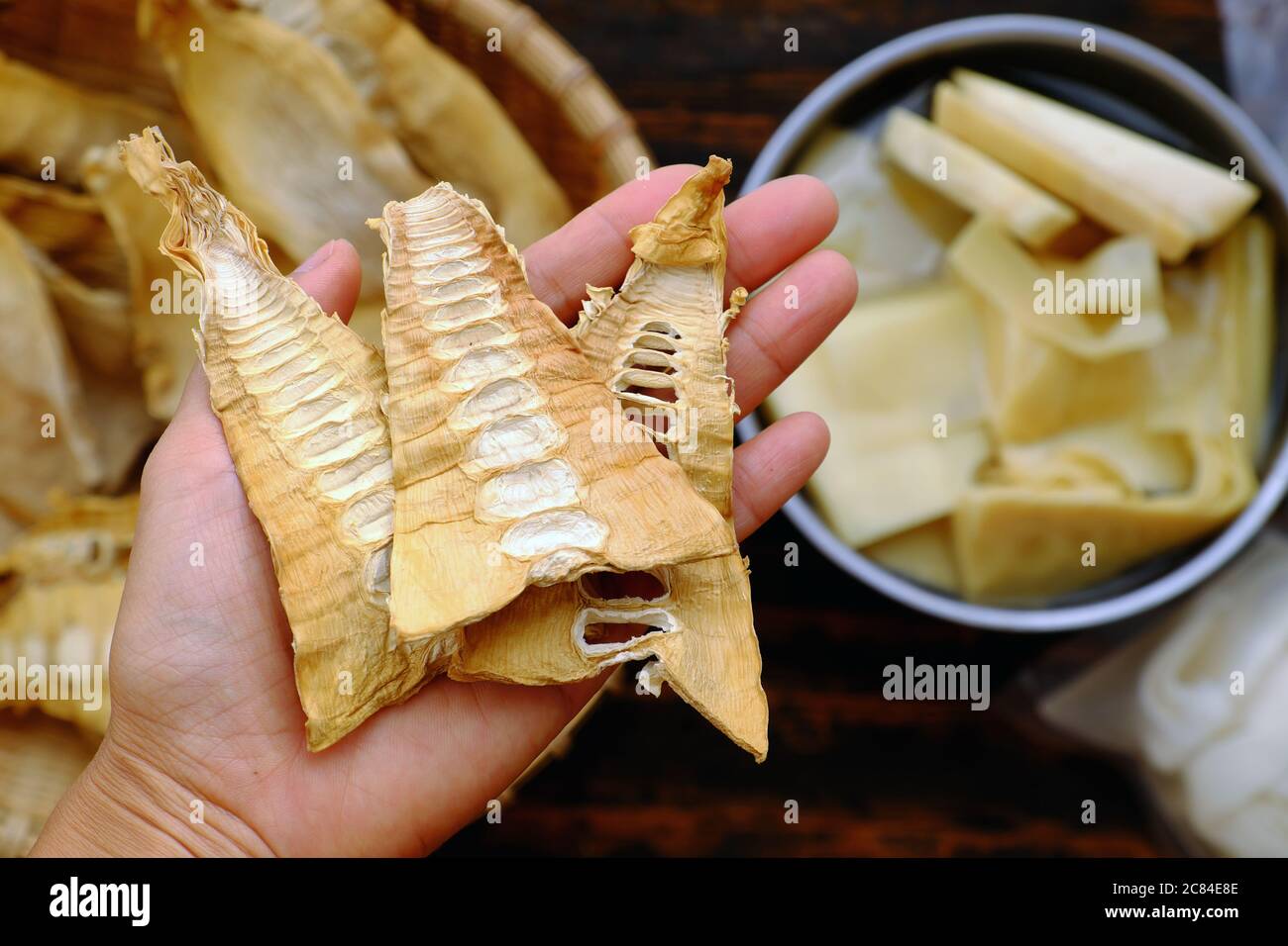 Top view close up woman hand hold dried bamboo shoots on bamboo background, raw material for