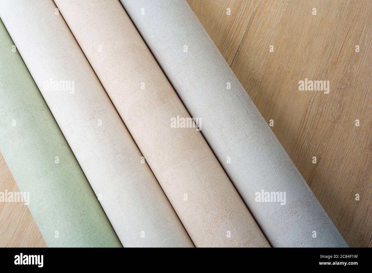 several rolls of multi-colored paper wallpaper on a wooden table Stock Photo