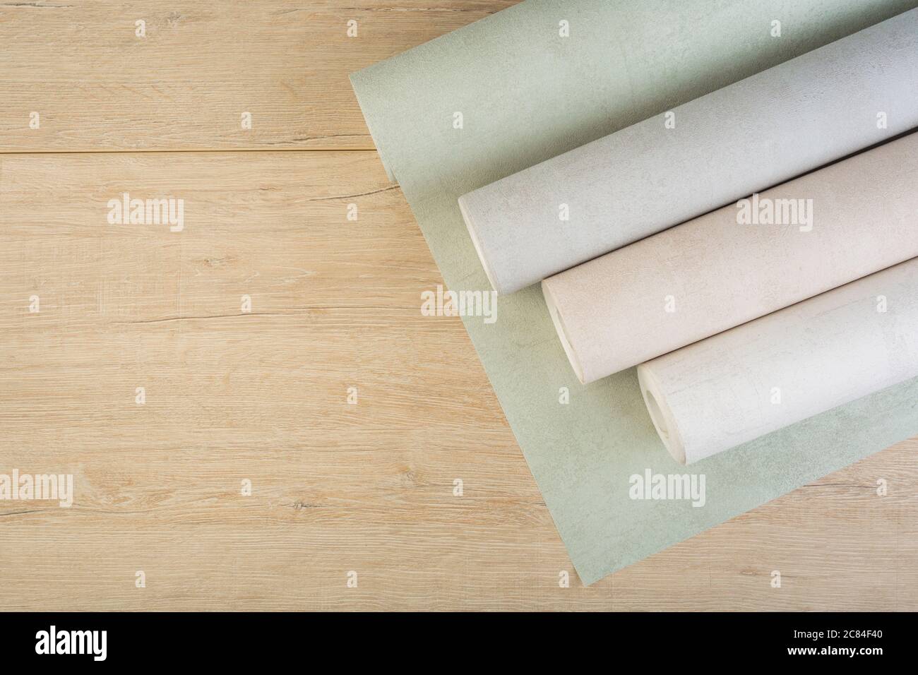 several rolls of multi-colored paper wallpaper on a wooden table Stock Photo