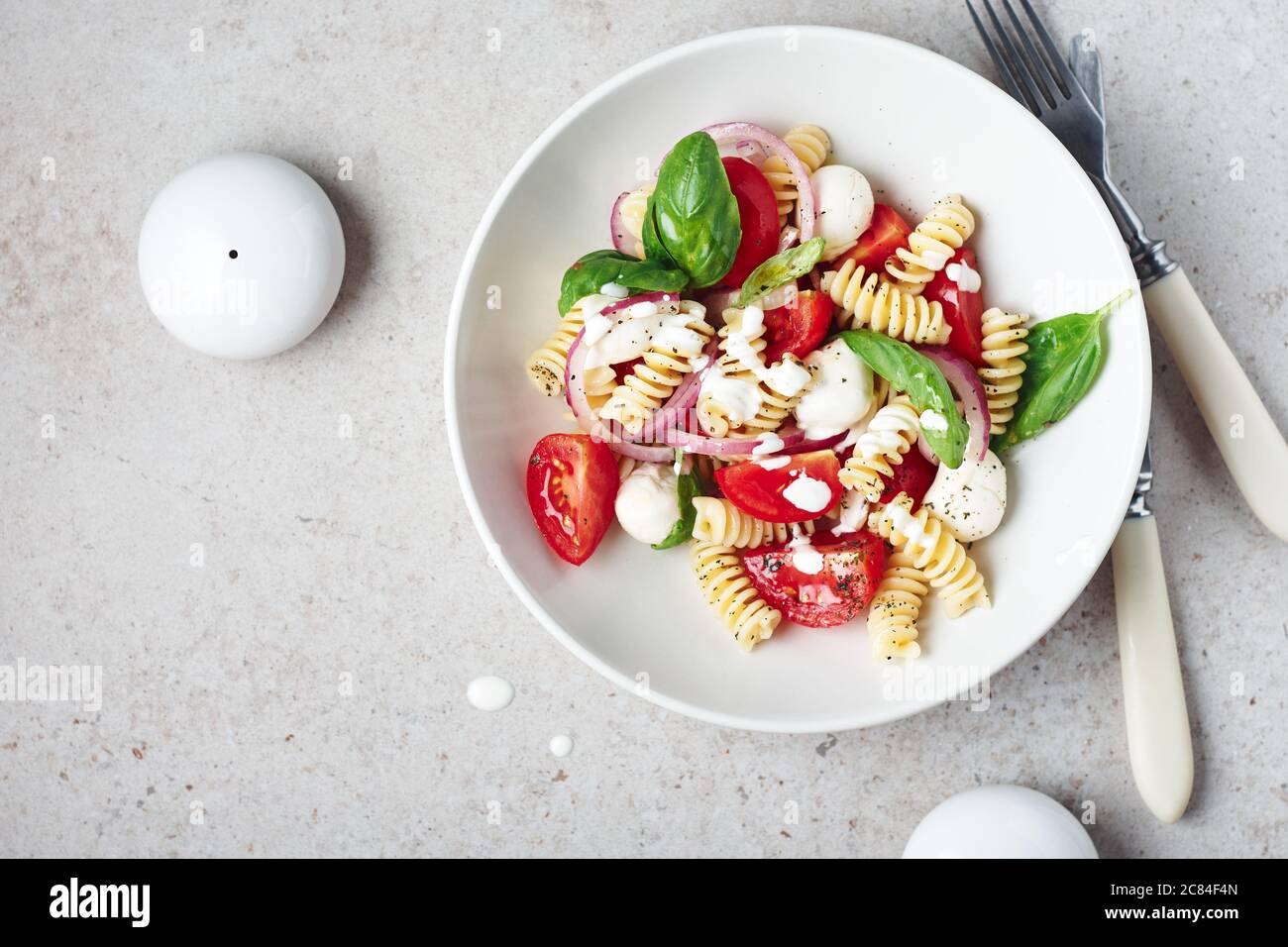 Pasta salad with tomatoes, mozzarella and basil leaves. Stock Photo