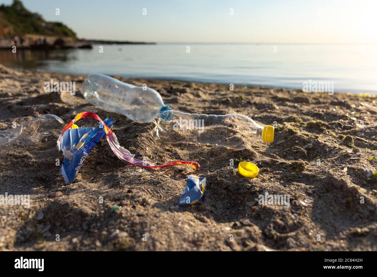 Polluted Beach With Plastic Garbage Lying On Sand Near Water Stock Photo