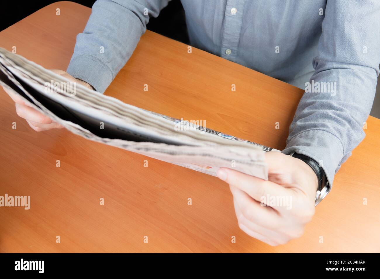 Man in grey shirt reading newspaper on the brown table Stock Photo