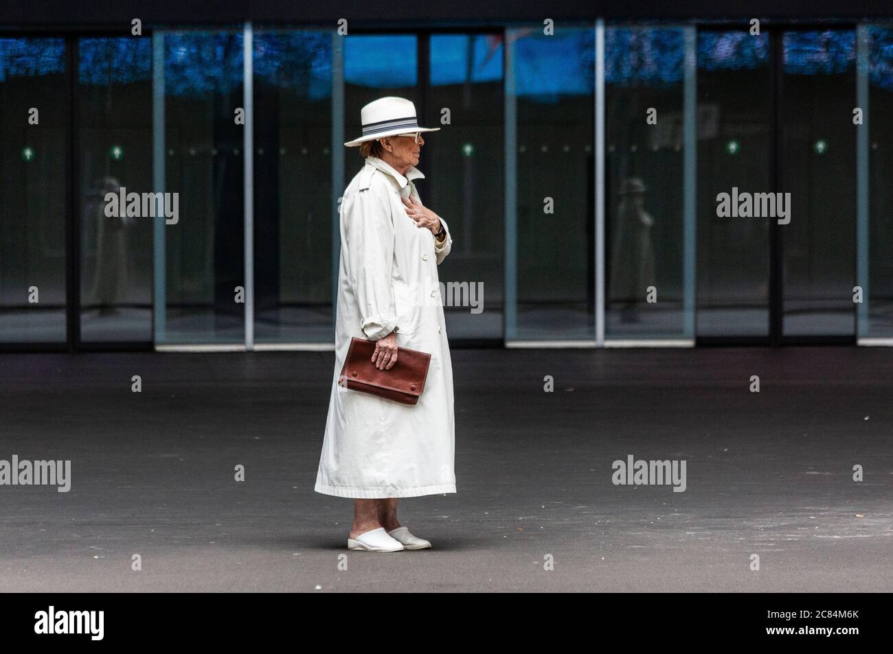 Fashionable woman standing alone wearing a stylish white raincoat Stock Photo