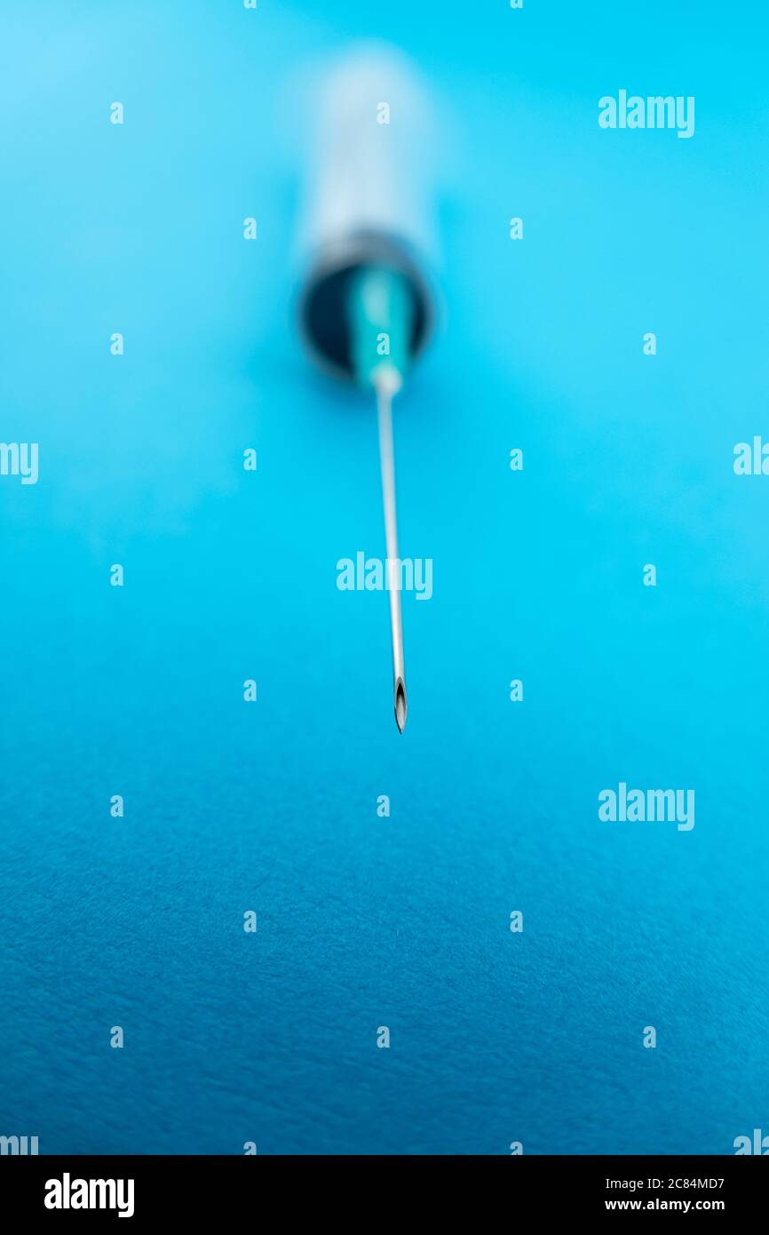 Plastic syringe needle stand close up isolated on blue background Stock Photo
