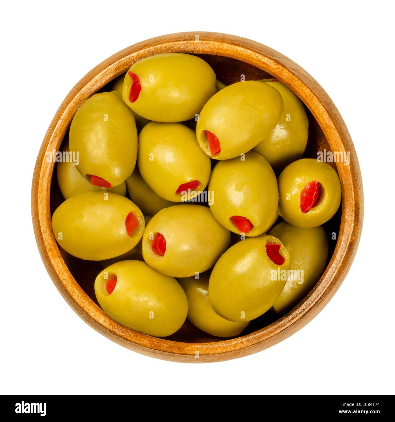 Sweet pepper stuffed green olives in wooden bowl. Big European olives, fruits of Olea europaea, filled with pickled red bell pepper slices. Stock Photo