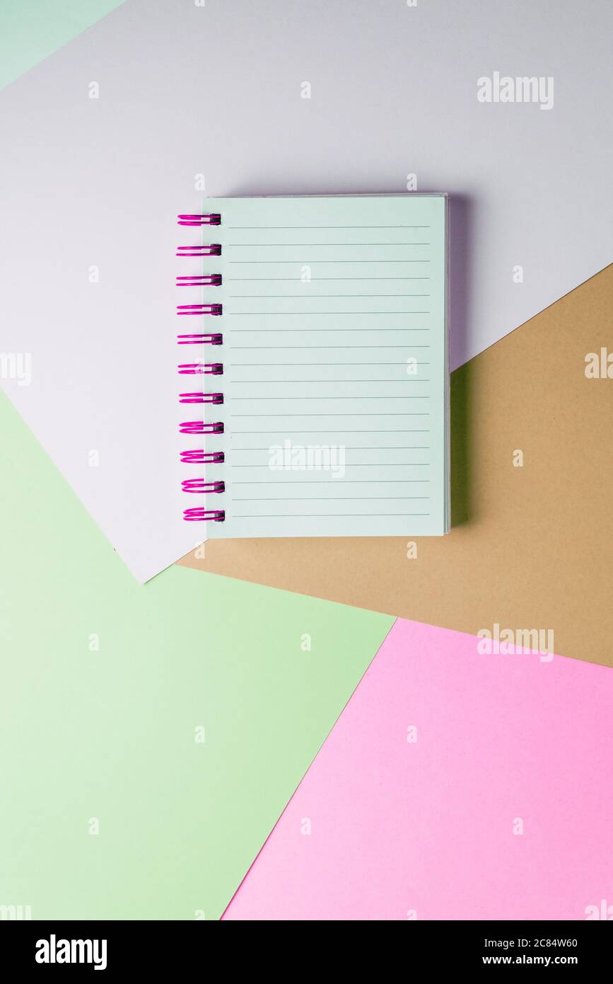 Open notebook with blank sheet and pink spiral on a colorful pastel background. The concept of education, writing down ideas, plans. Place for text. M Stock Photo