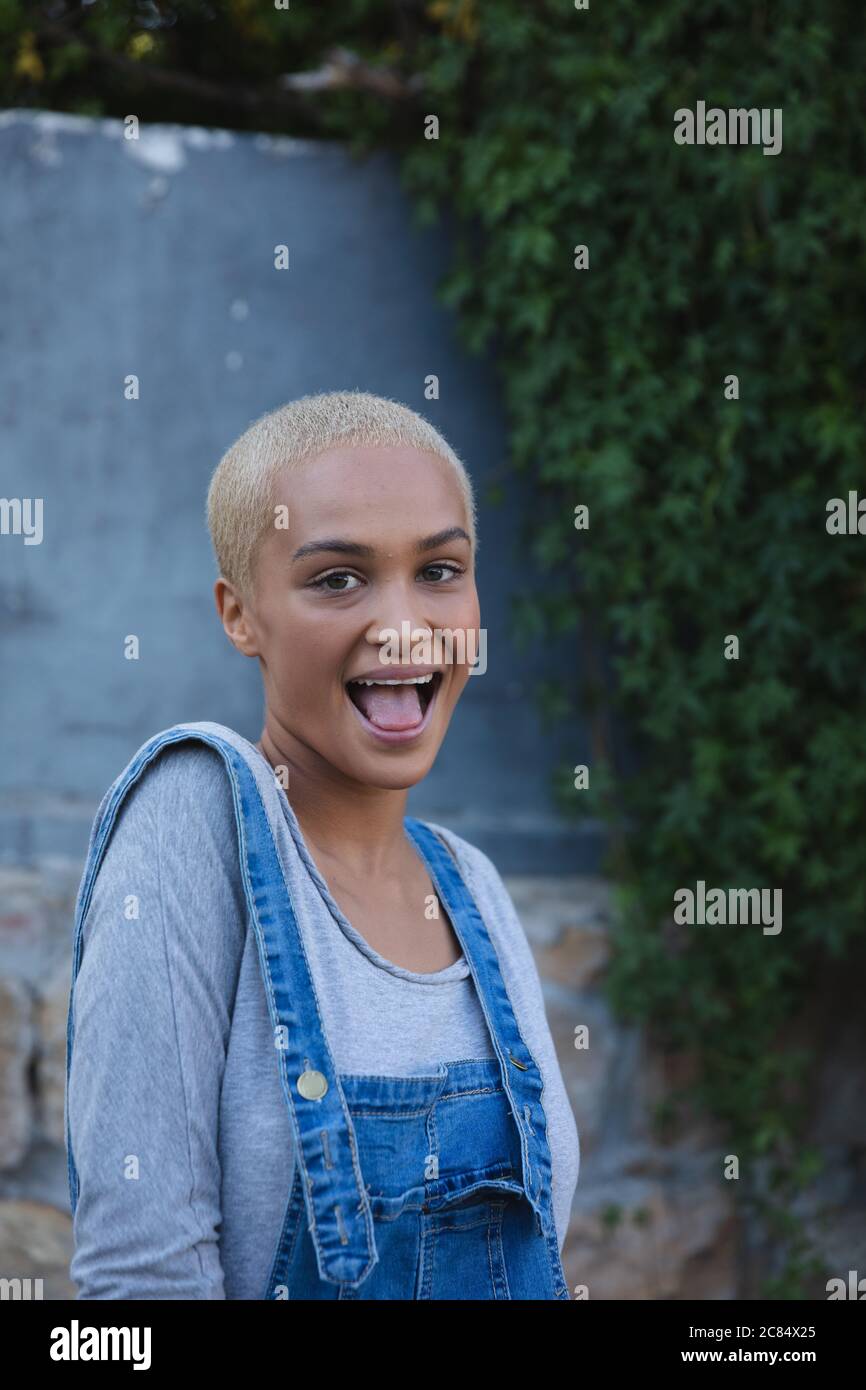 Portrait Of Mixed Race Alternative Woman With Short Blonde Hair And Denim Dungarees Out And About In The City On A Sunny Day Smiling To Camera Urban Stock Photo Alamy
