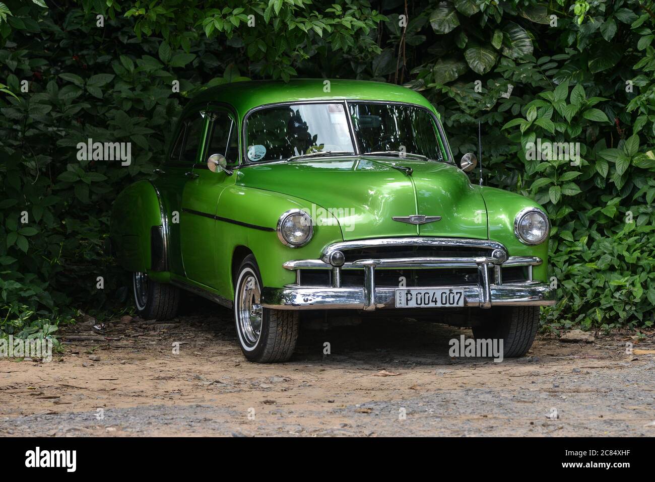 Cuba: classic American cars in the countryside. Gleaming apple-green 1951 Chevrolet parked in the middle of bushes Stock Photo