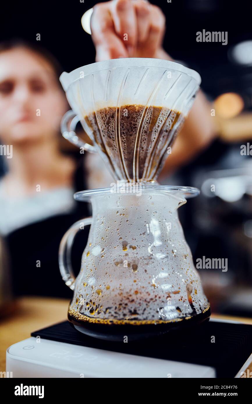 Drip coffee making with a funnel shaped filter paper on a glass vessel Stock Photo