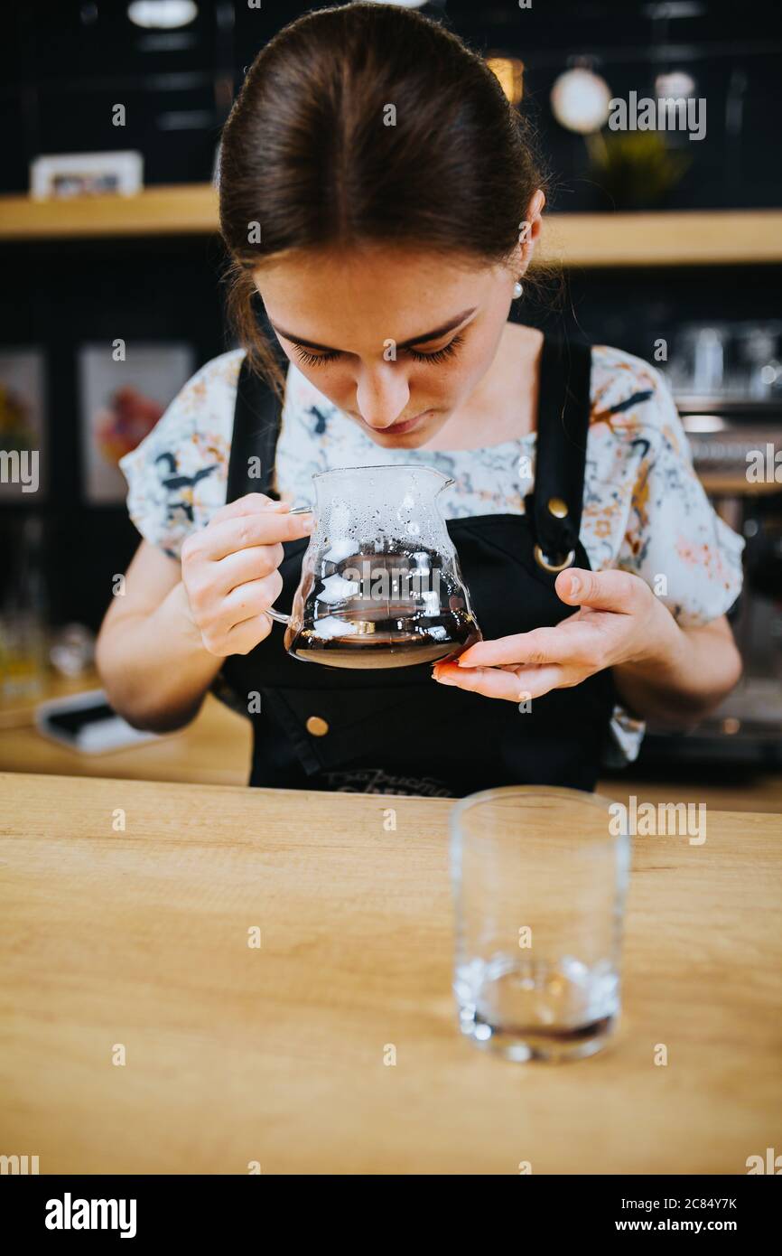 Barista girl sniffing brewed coffee in a glass jug drip coffee making
