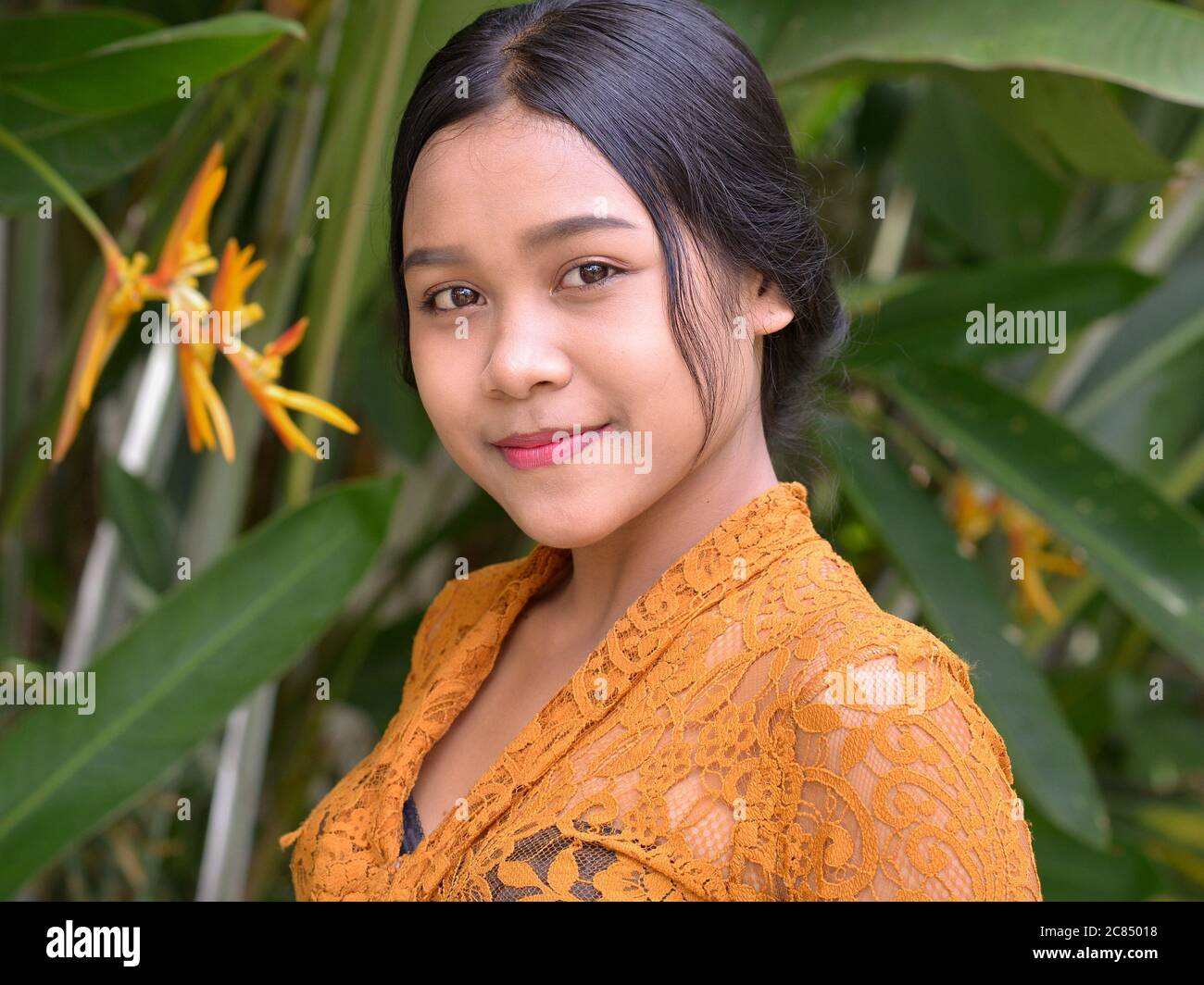 Indonesian Balinese girl wears a traditional Indonesian kebaya lace blouse and poses for the camera. Stock Photo