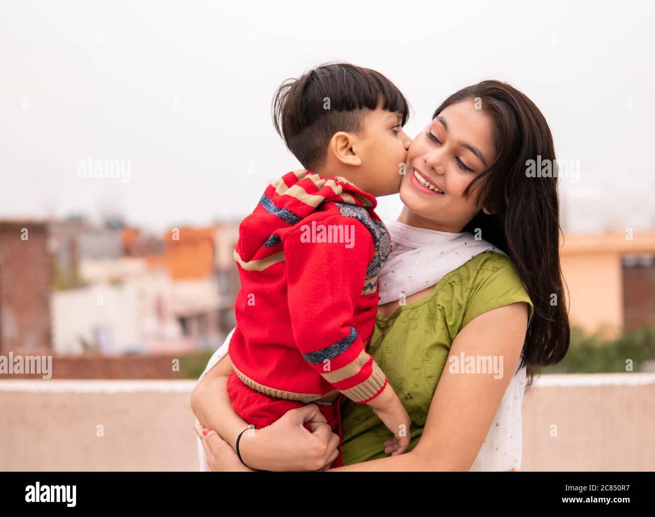 Cute little nephew kissing on his aunt cheeks. She is wearing traditional Indian dress salwar Kameez and Dupatta. Stock Photo