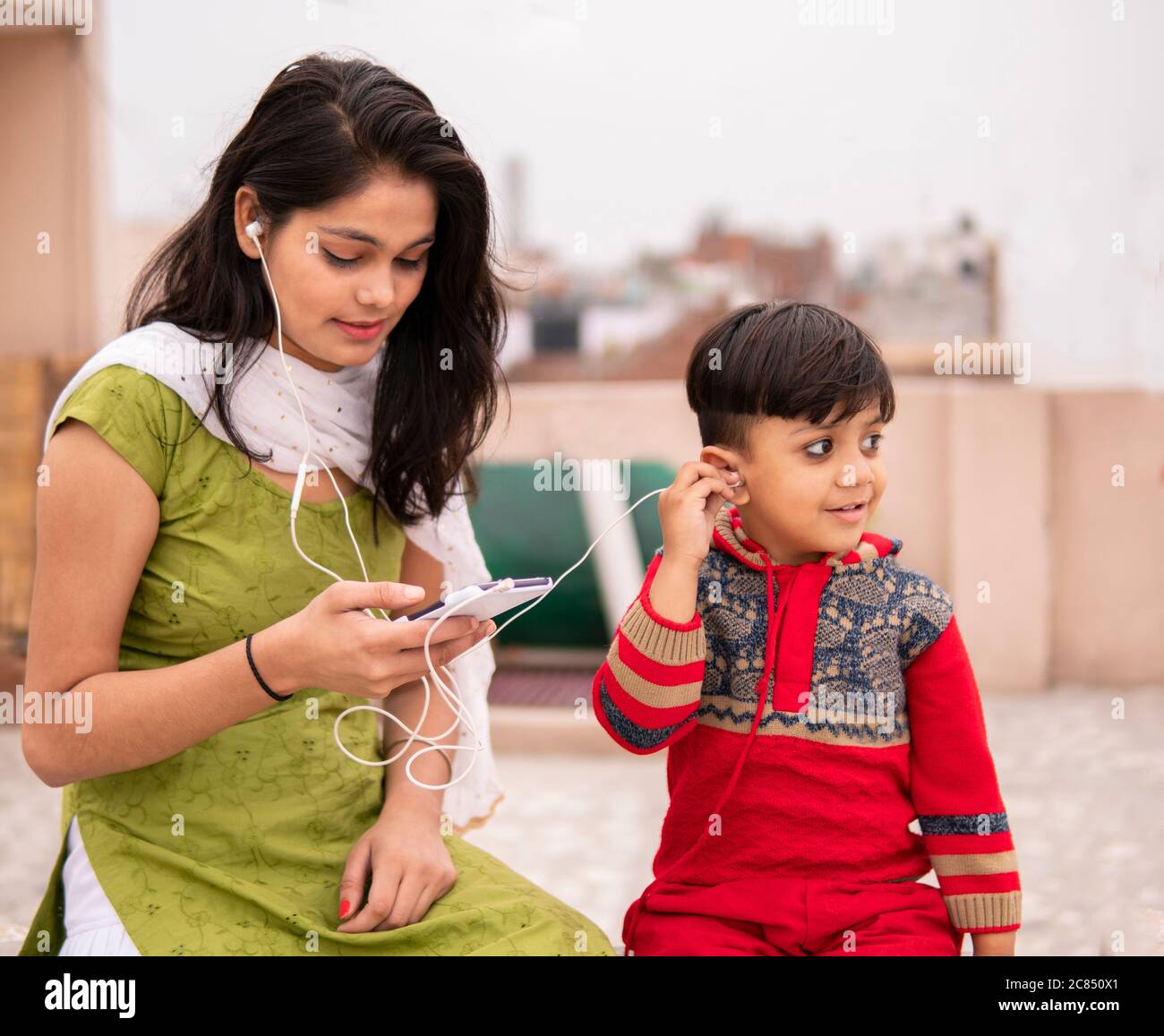 Rear view of an aunt holding her cut little nephew in outdoor. She is wearing traditional Indian dress salwar Kameez and Dupatta. Stock Photo