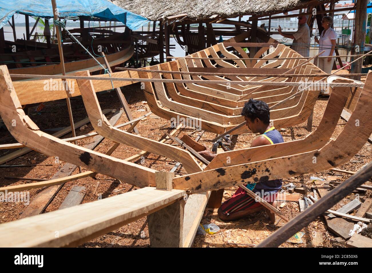 A boat builder works on the skeleton on a new wooden canoe at a boat building yard in Macapa in Amapa State, Brazil Stock Photo