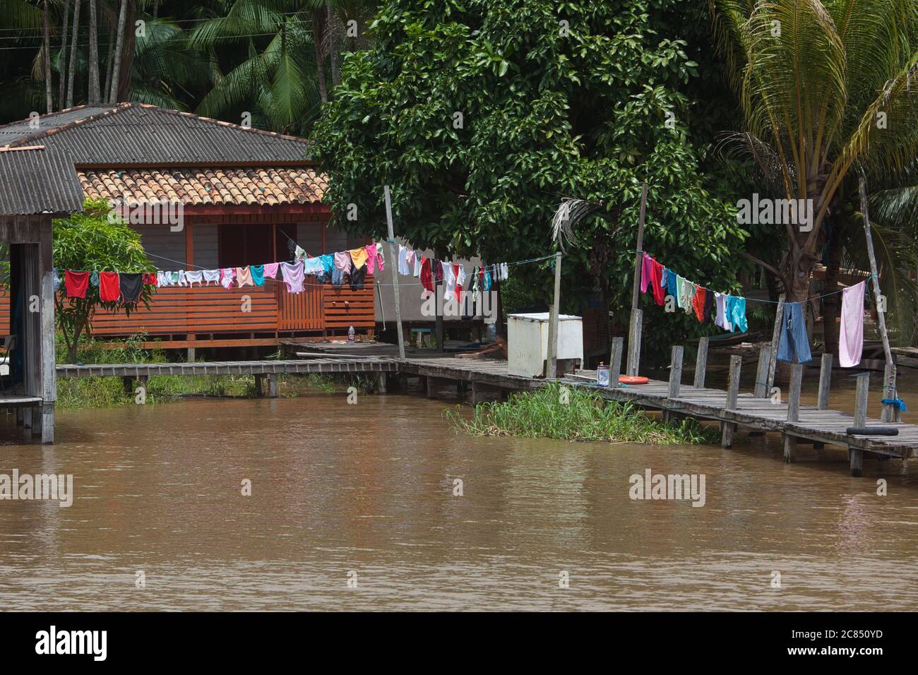 A typical house on stilts and jetty with washing lines hanging, on the banks of the River Amazon near Macapa in Amapa State, Brazil Stock Photo