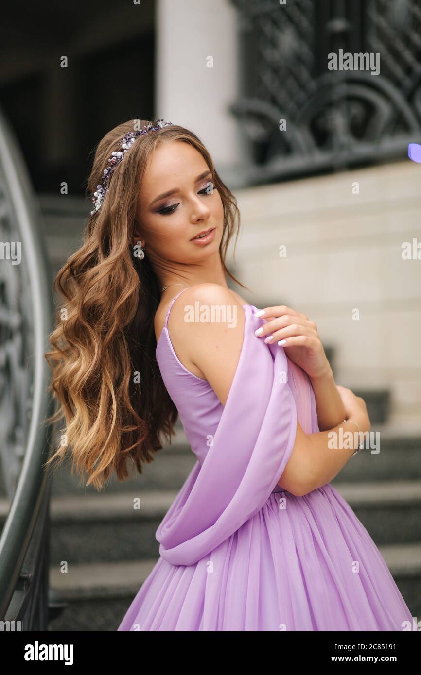 Portrait of elegant woman in purple evening dress walking outdoors by ...