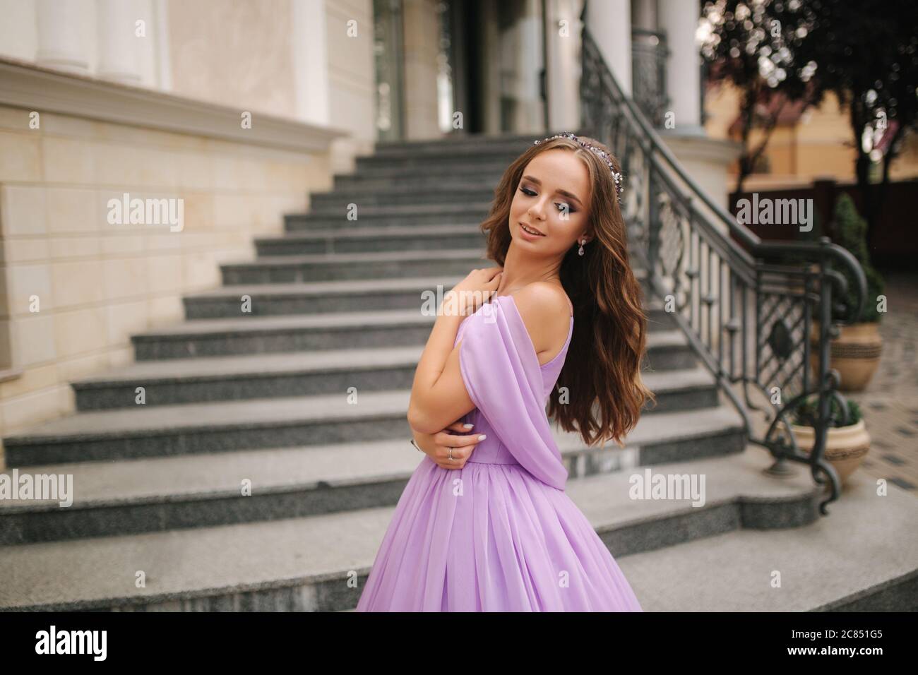 Portrait of elegant woman in purple evening dress walking outdoors by ...