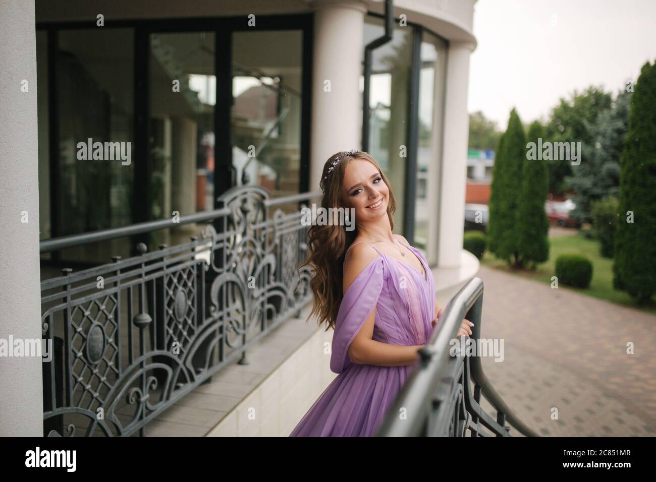 Portrait of elegant woman in purple evening dress walking outdoors by ...