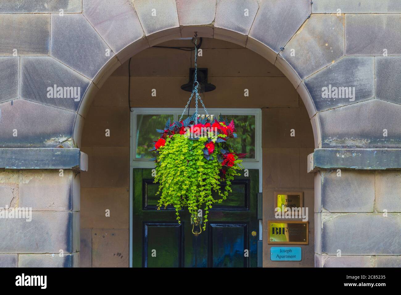 Colourful Flowers in Hanging Basket Beneath Stone Arch in The Square, Buxton. Stock Photo