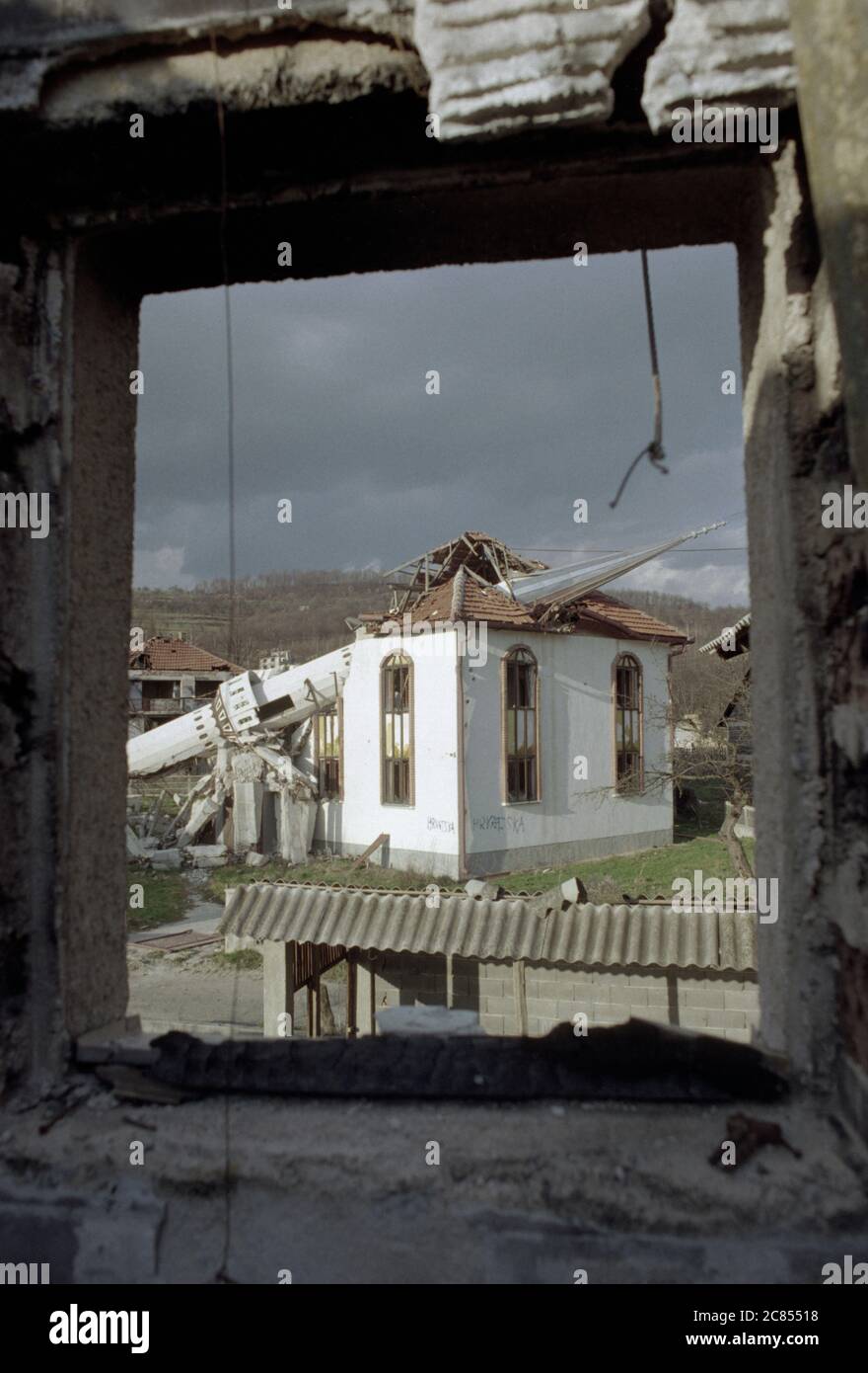 17th March 1994 During the war in Bosnia: framed through the window of a burned-out house, the destroyed Donji Ahmići mosque in Ahmići, a few miles east of Vitez, in central Bosnia, where the Bosnian Croats (HVO) 'ethnically cleansed' the village on the 16th April 1993, murdering more than one hundred people. Stock Photo