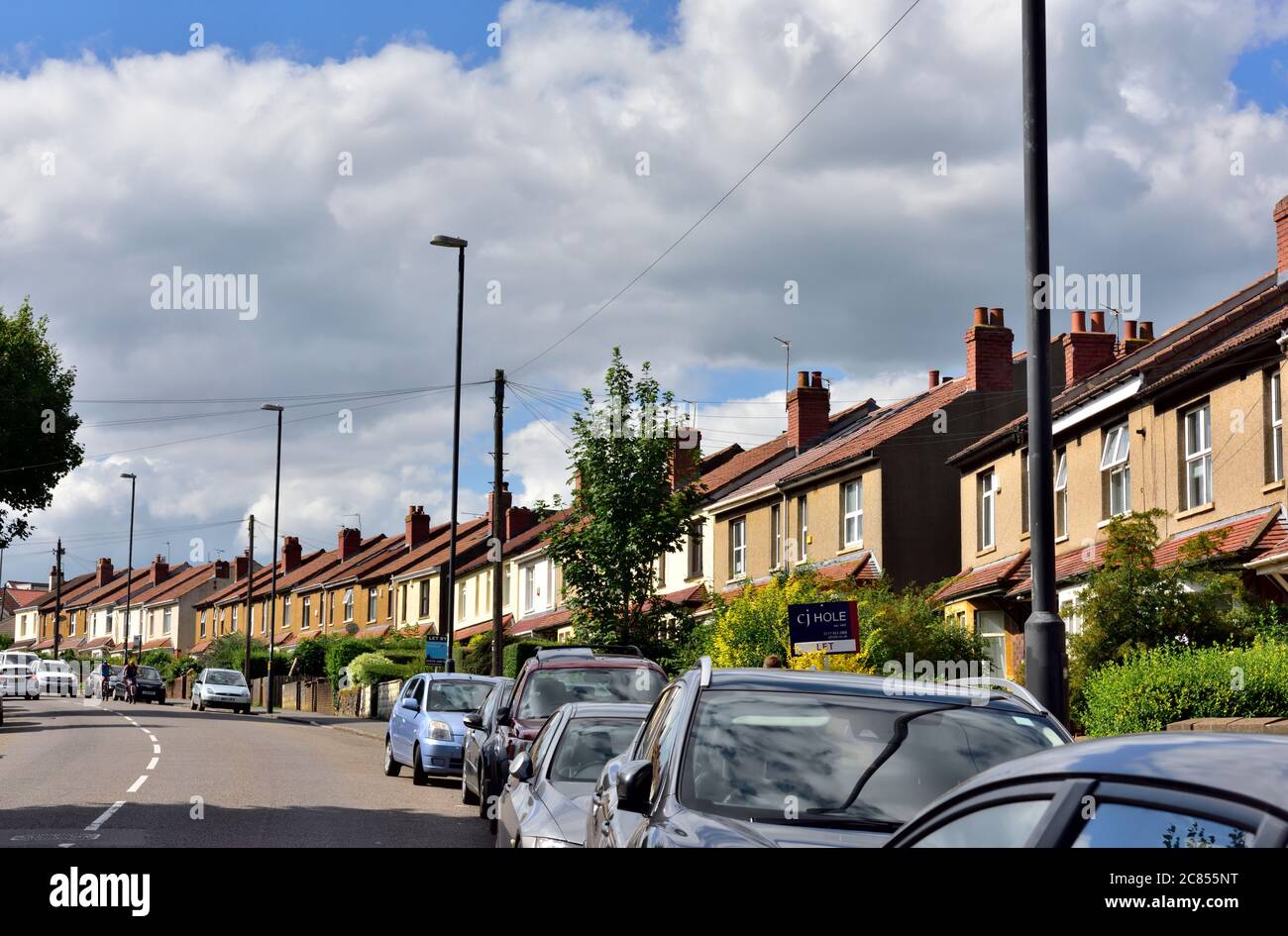 Row of terraced houses with cars parked in front along street, Horfield, Bristol Stock Photo