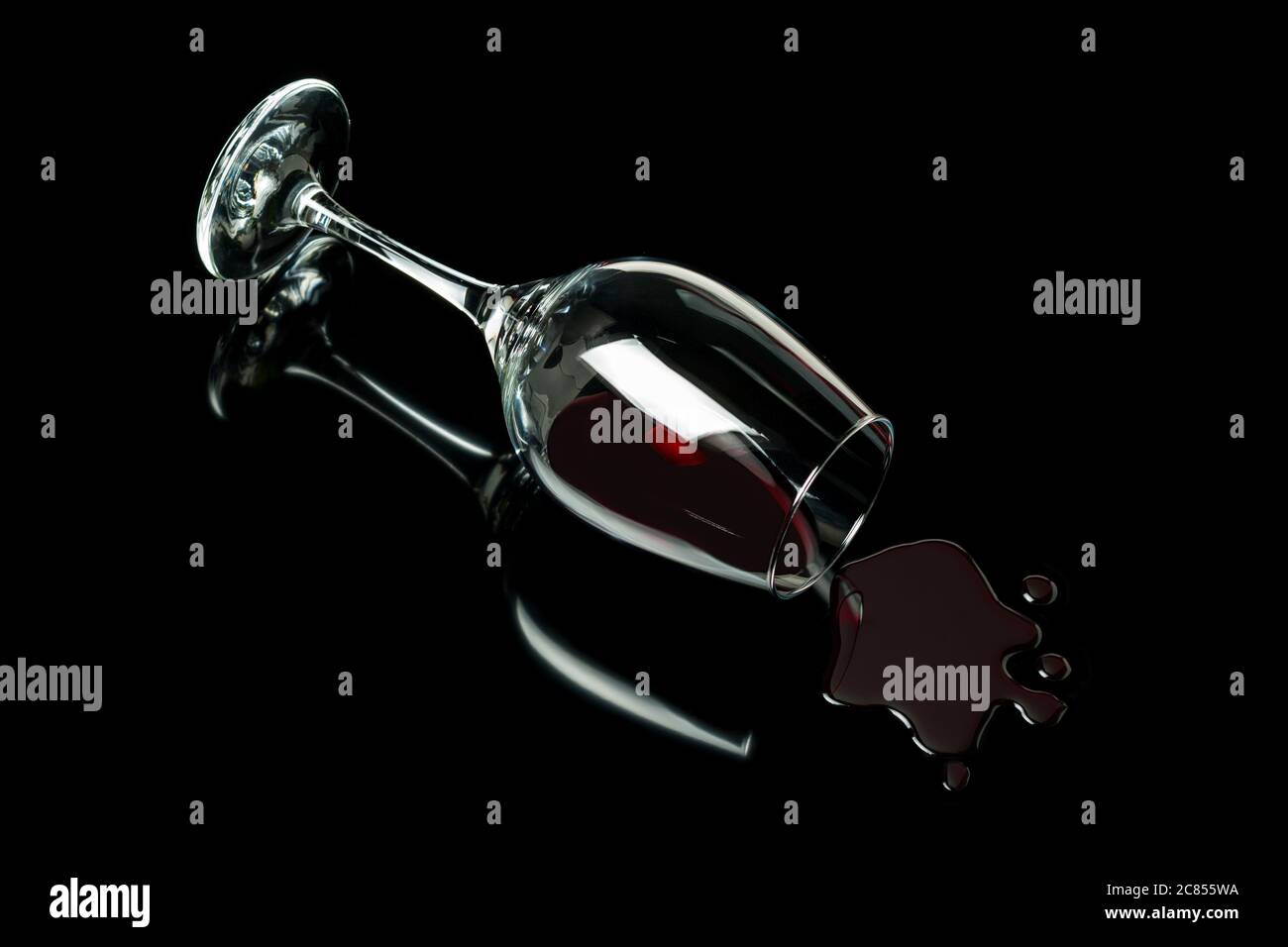 Spilled wine glass on a black background with reflection. Alcohol abuse concept. Stock Photo